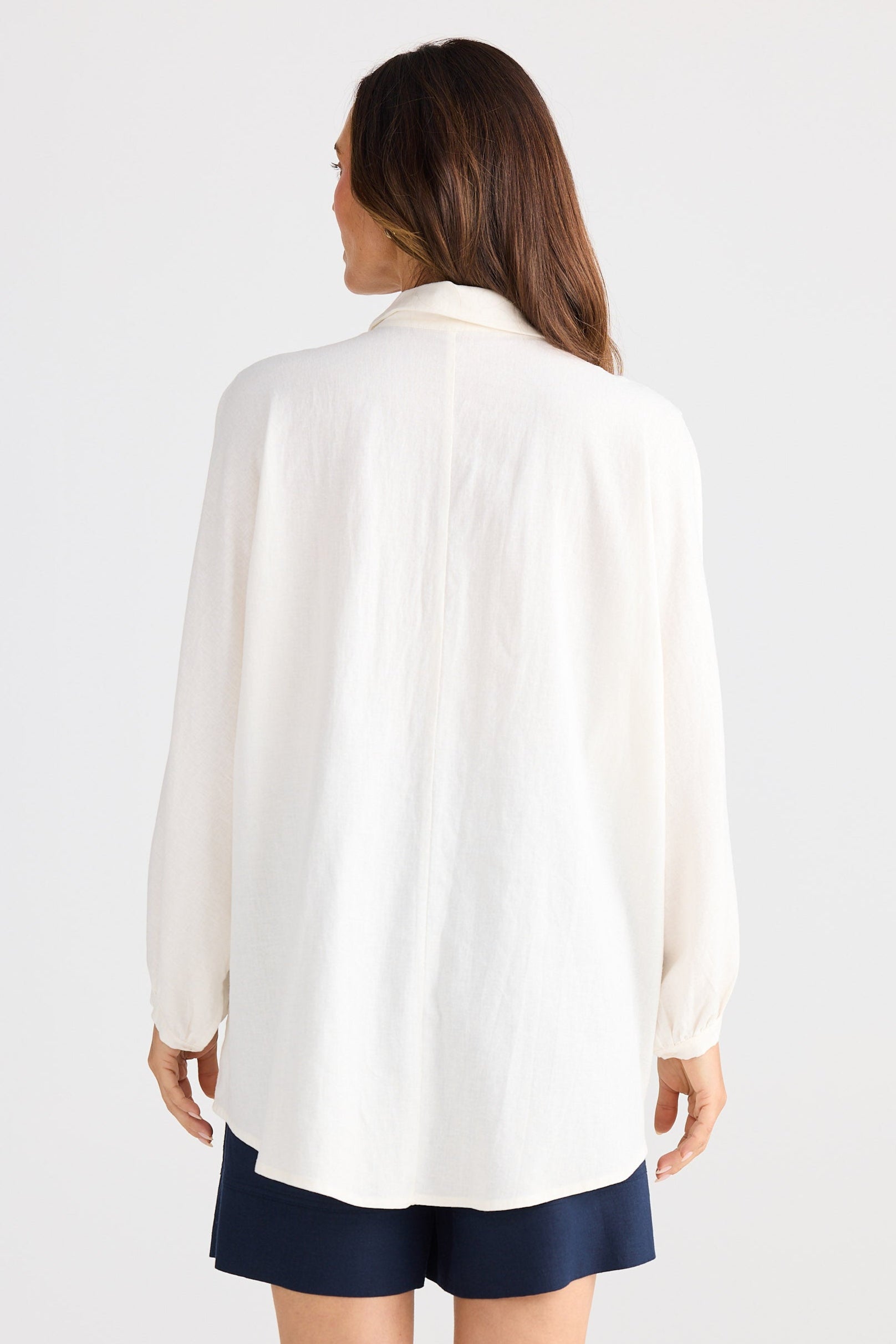 Woman wearing a white blouse and navy shorts on a white background