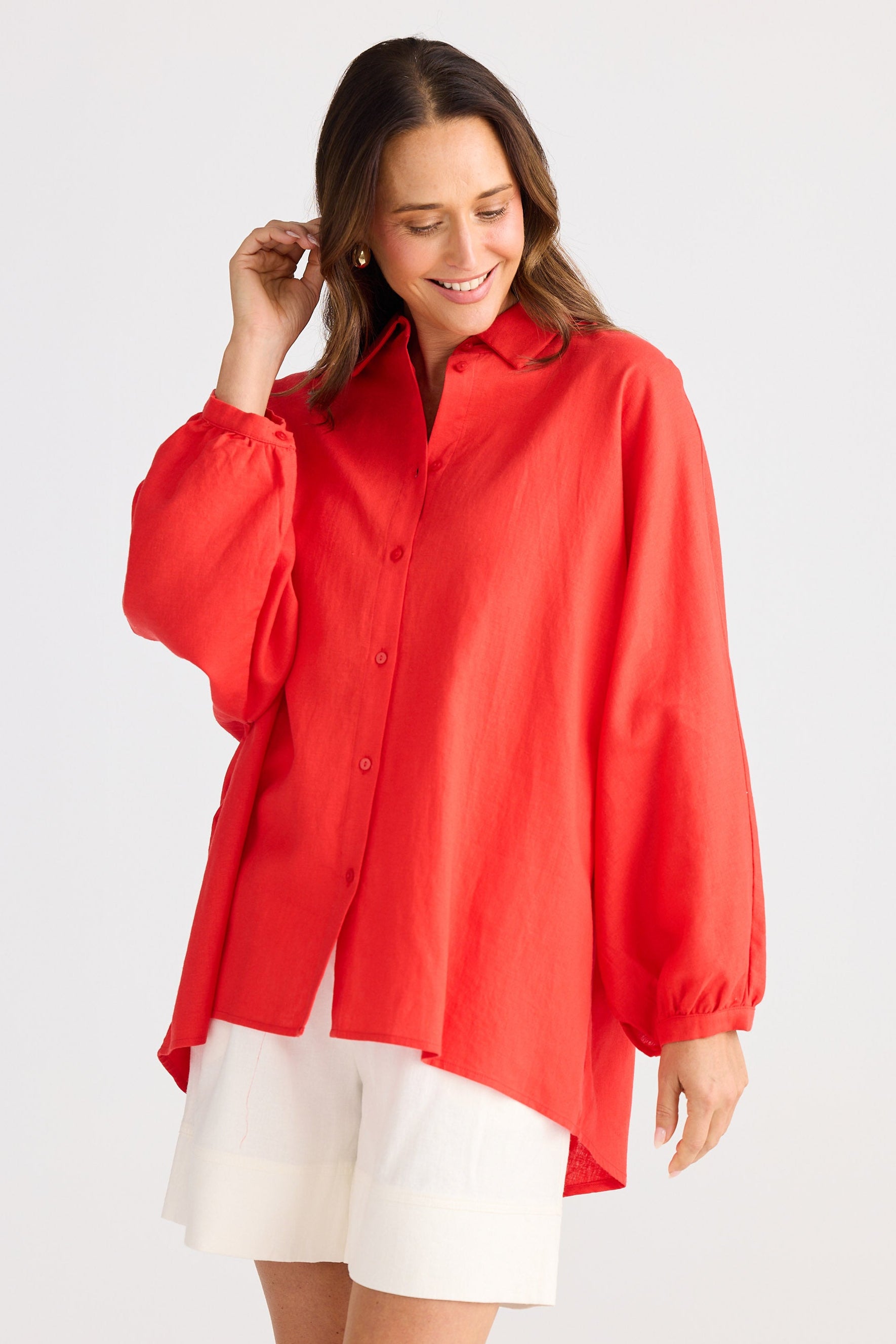 Woman wearing a red blouse and white shorts on a plain background