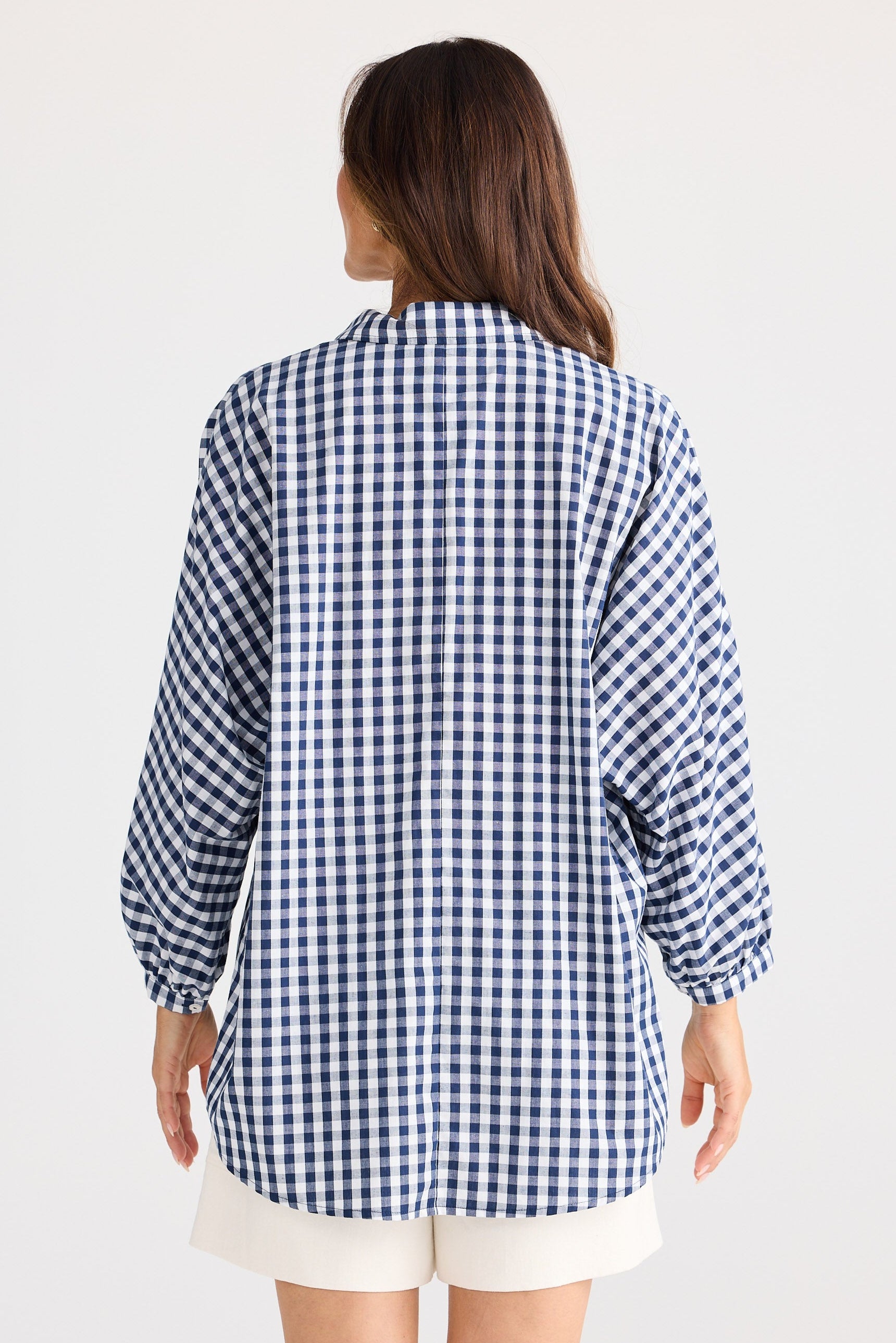 Person wearing a blue and white checkered shirt on a light gray background