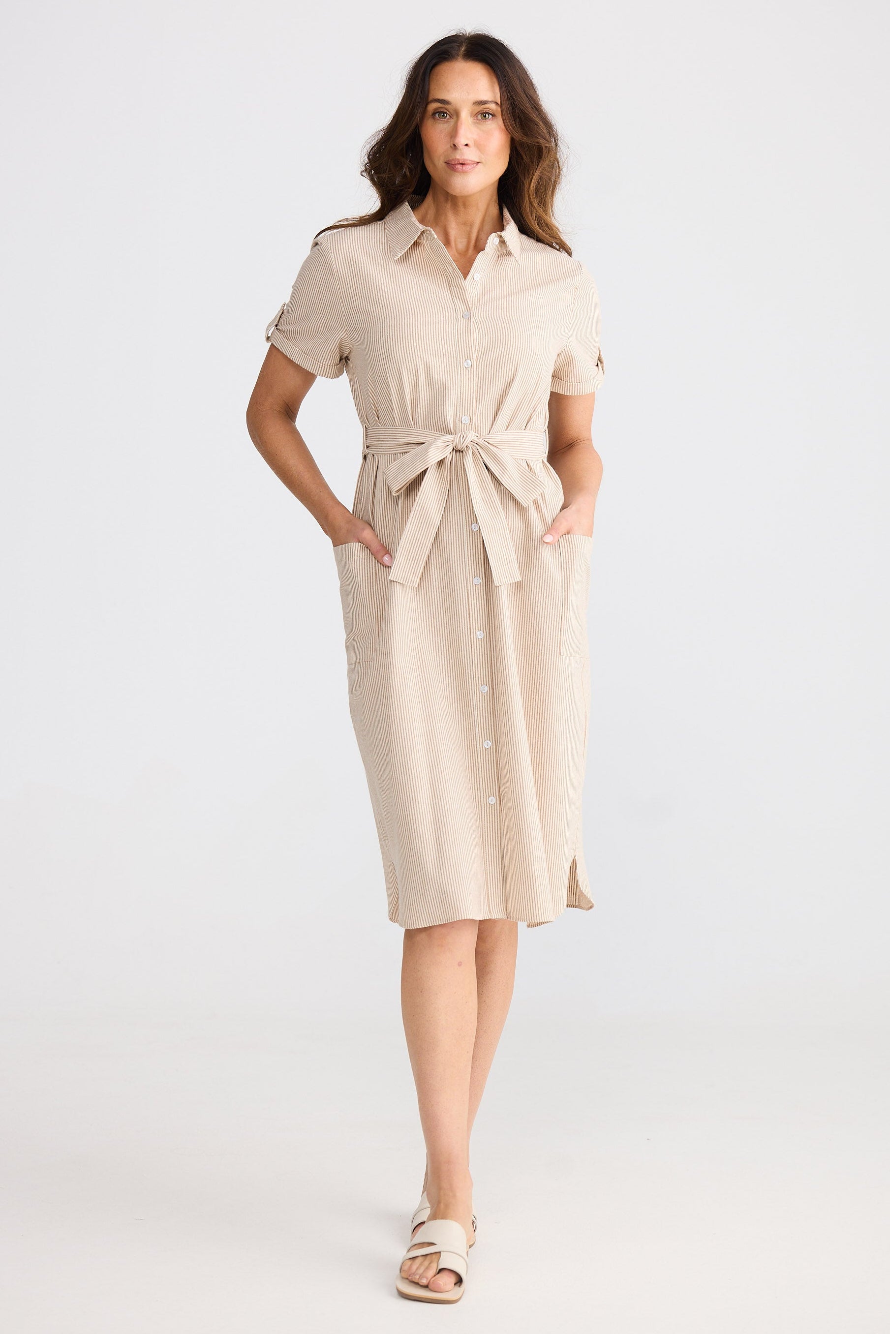 Woman wearing a beige striped shirt dress on a white background