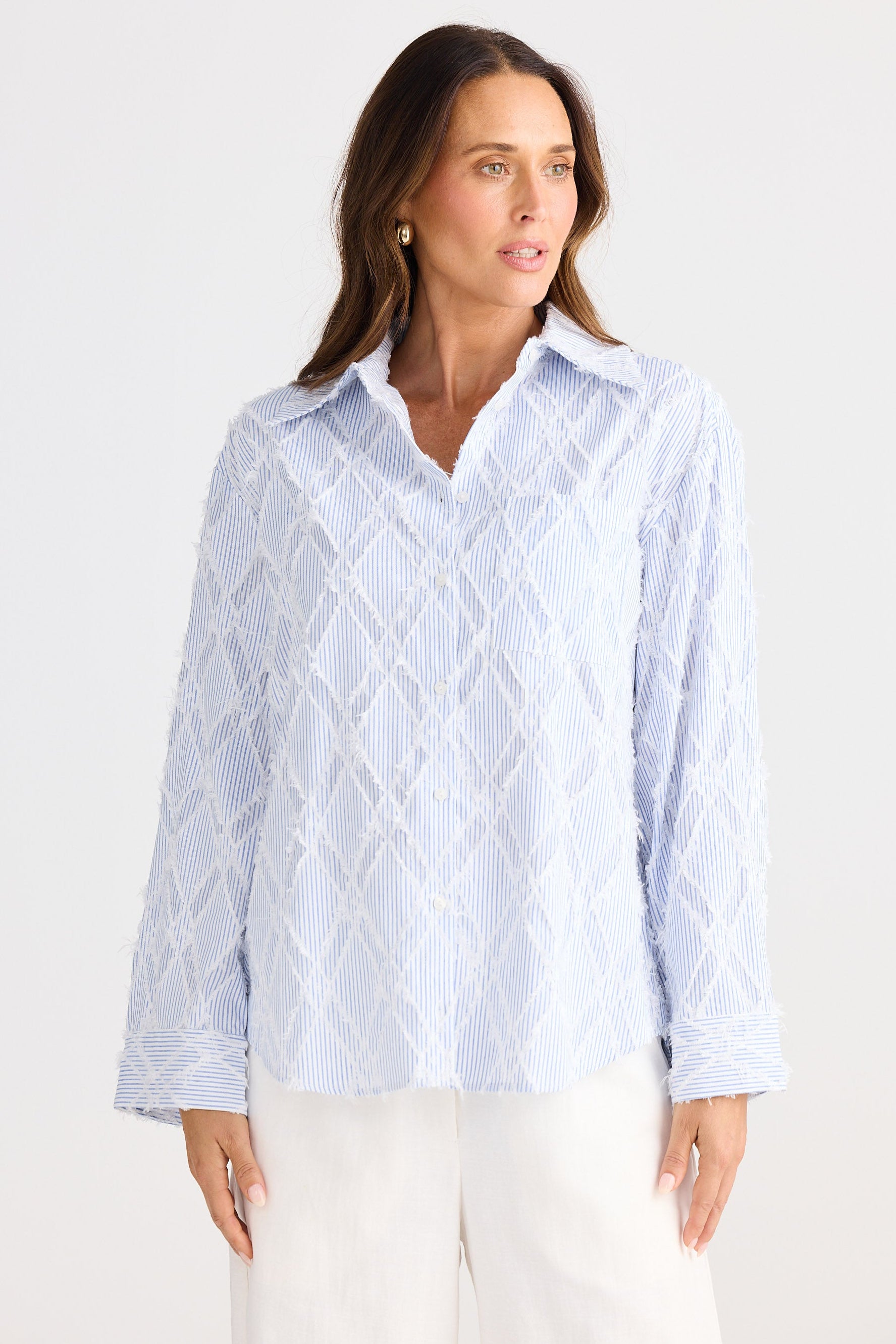 Woman wearing a light blue patterned shirt against a white background