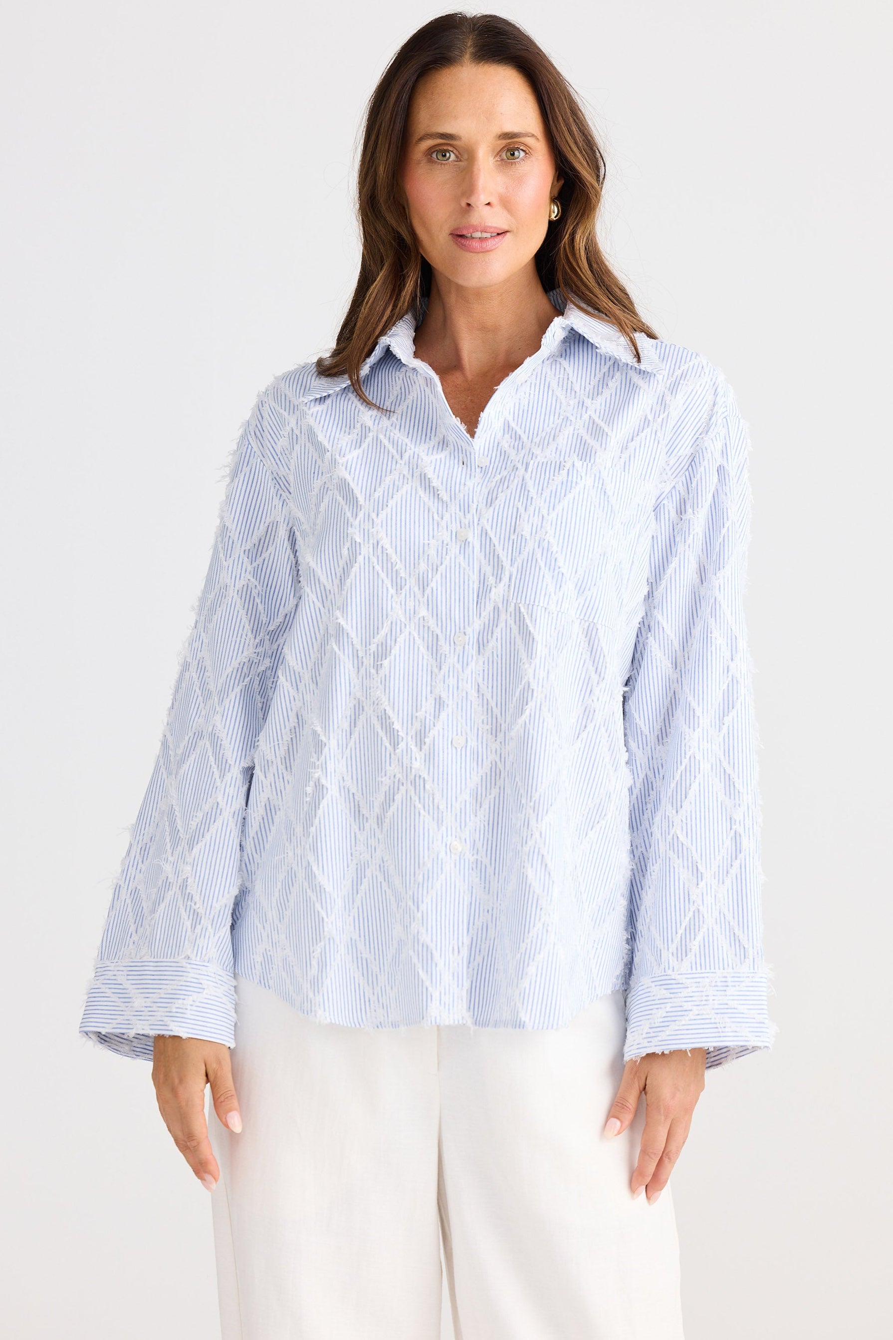 Woman wearing a light blue patterned shirt on a white background