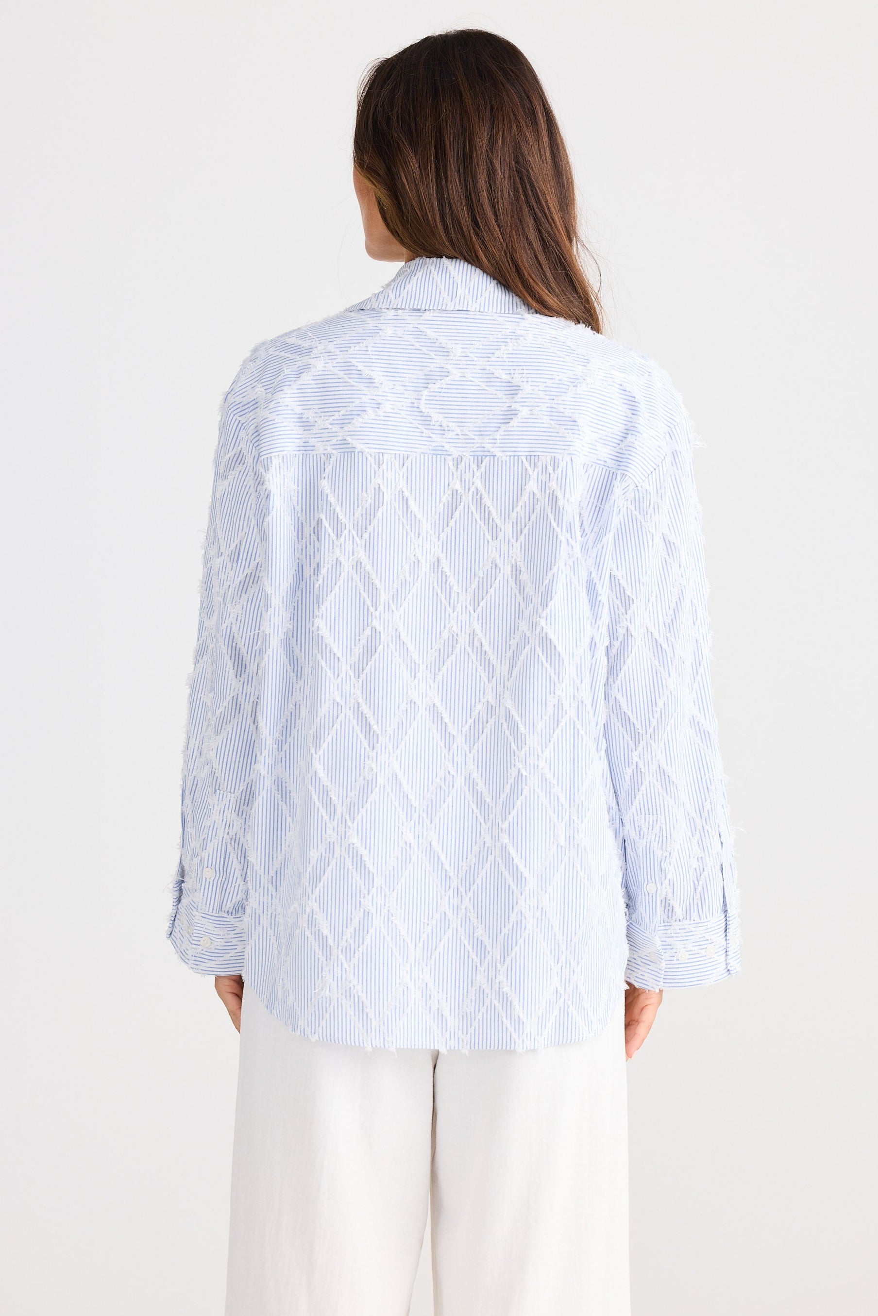 Person wearing a light blue textured shirt on a white background
