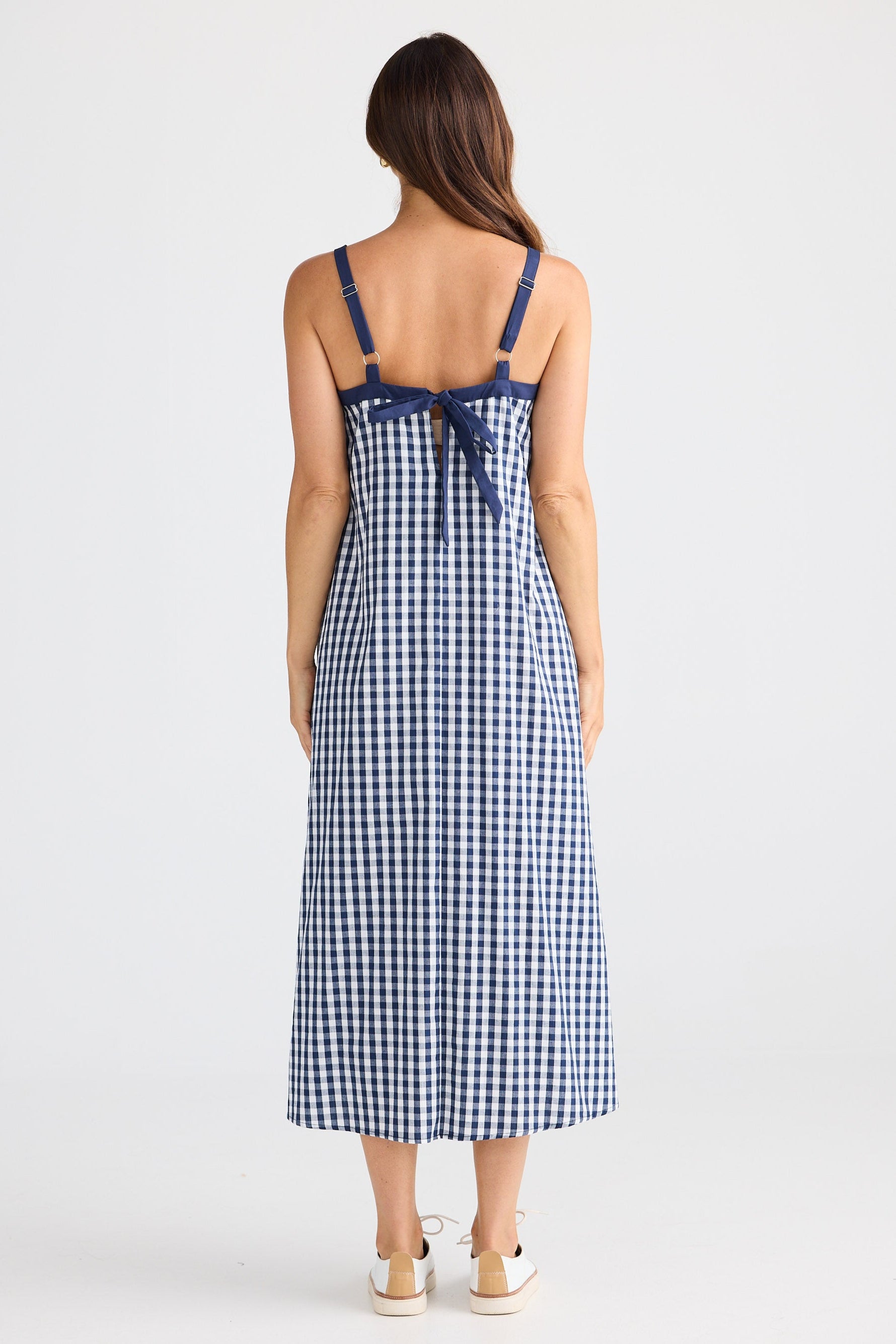 Woman wearing a blue and white checkered dress with a bow detail on a white background