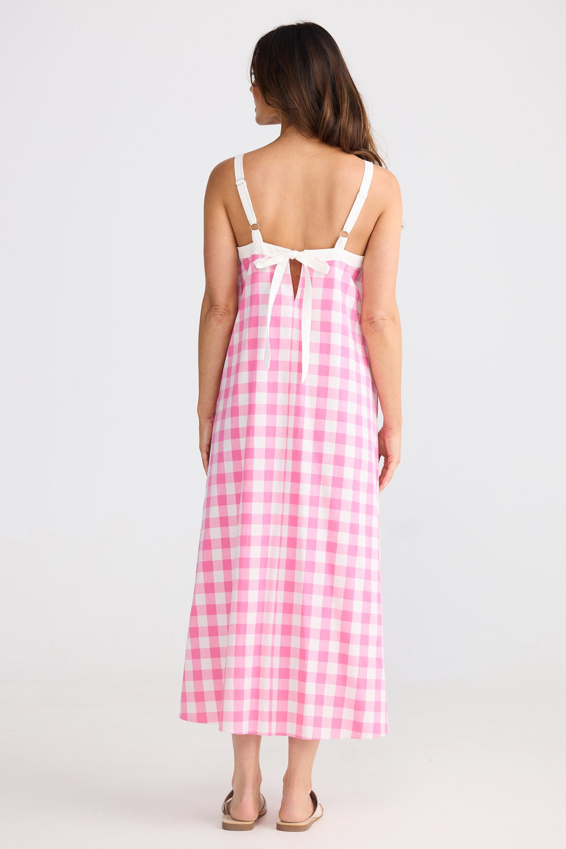 Woman wearing a pink and white checkered dress on a white background
