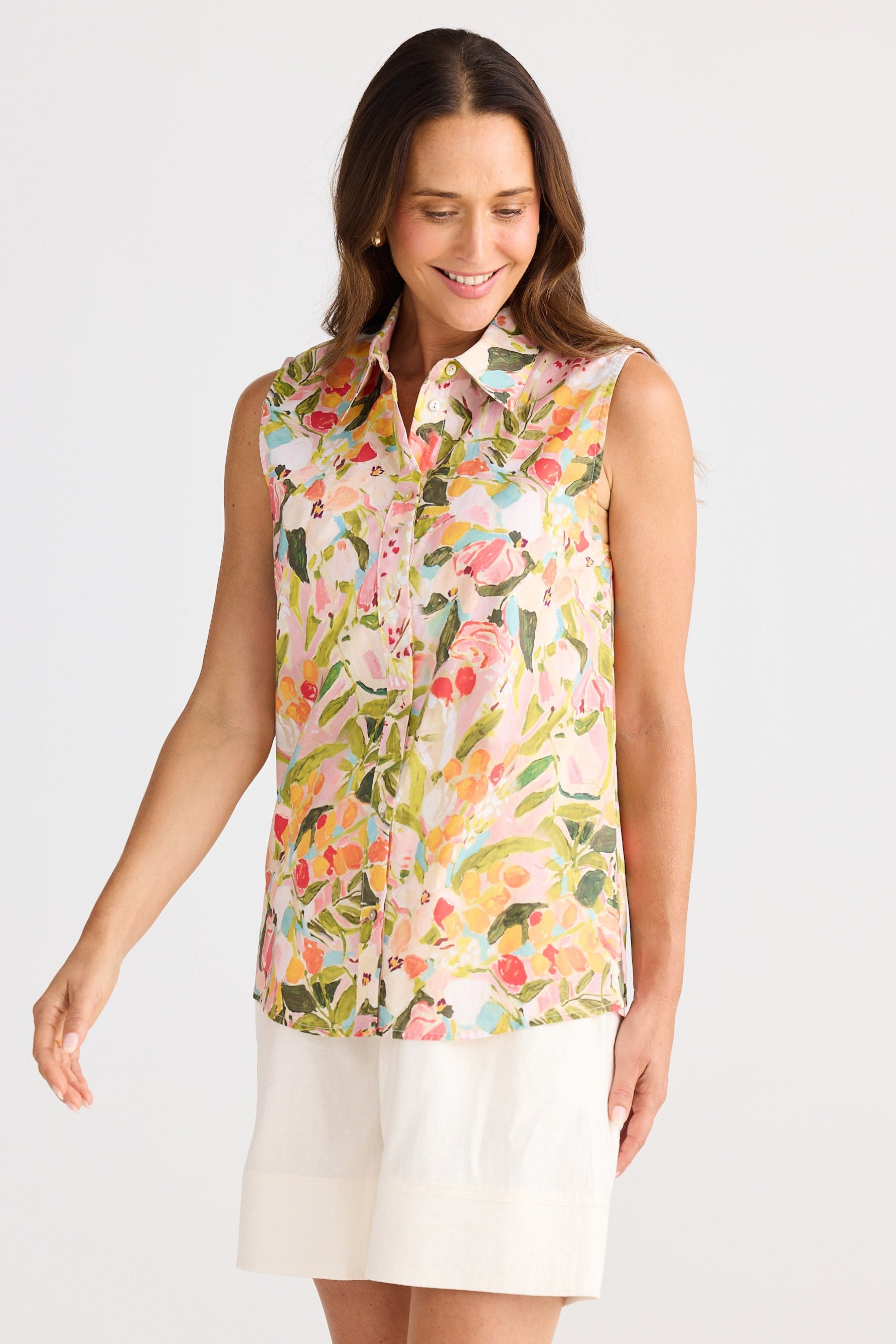 Woman wearing a sleeveless floral blouse with a white skirt on a light gray background