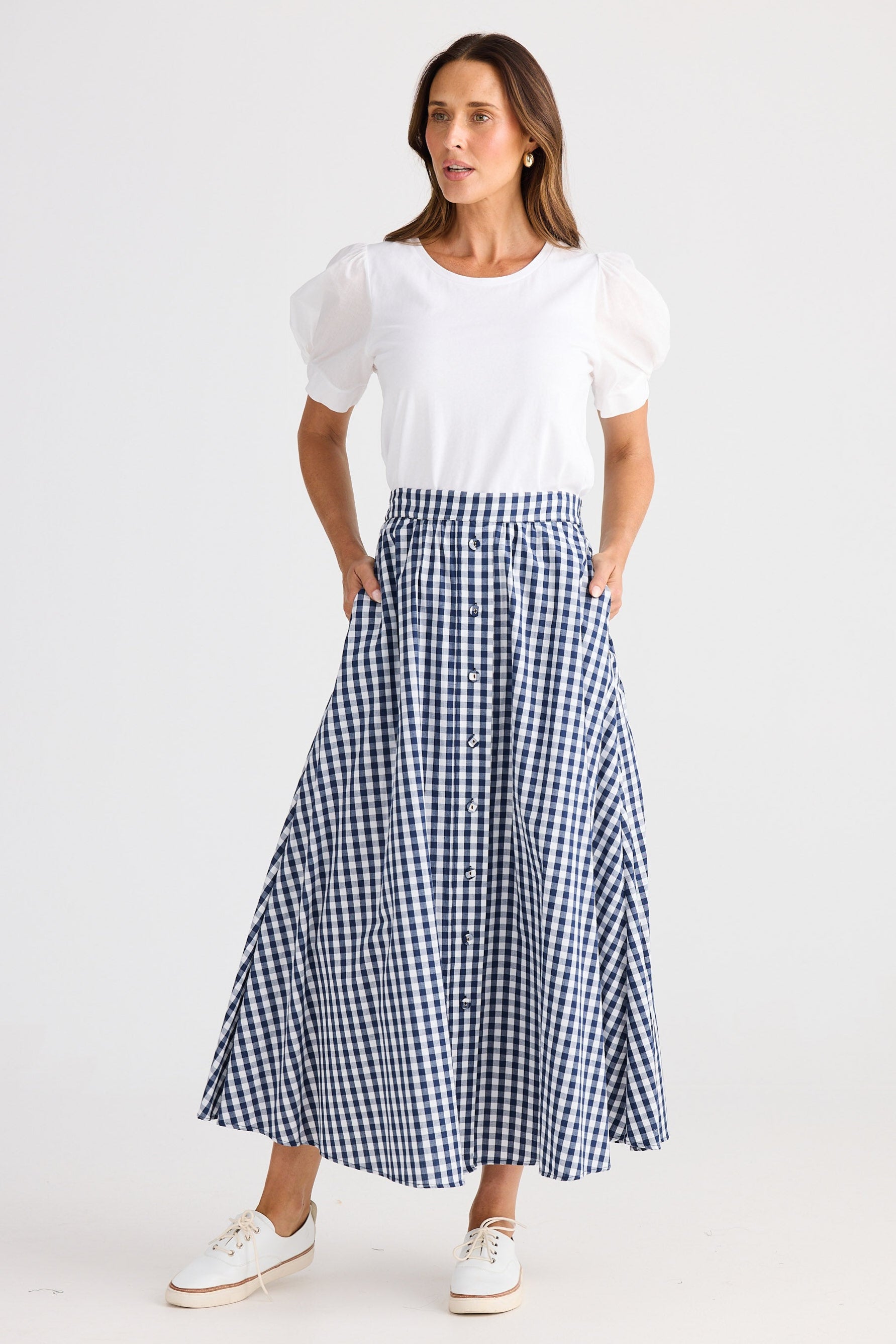 Woman wearing a white top and blue checkered skirt on a white background