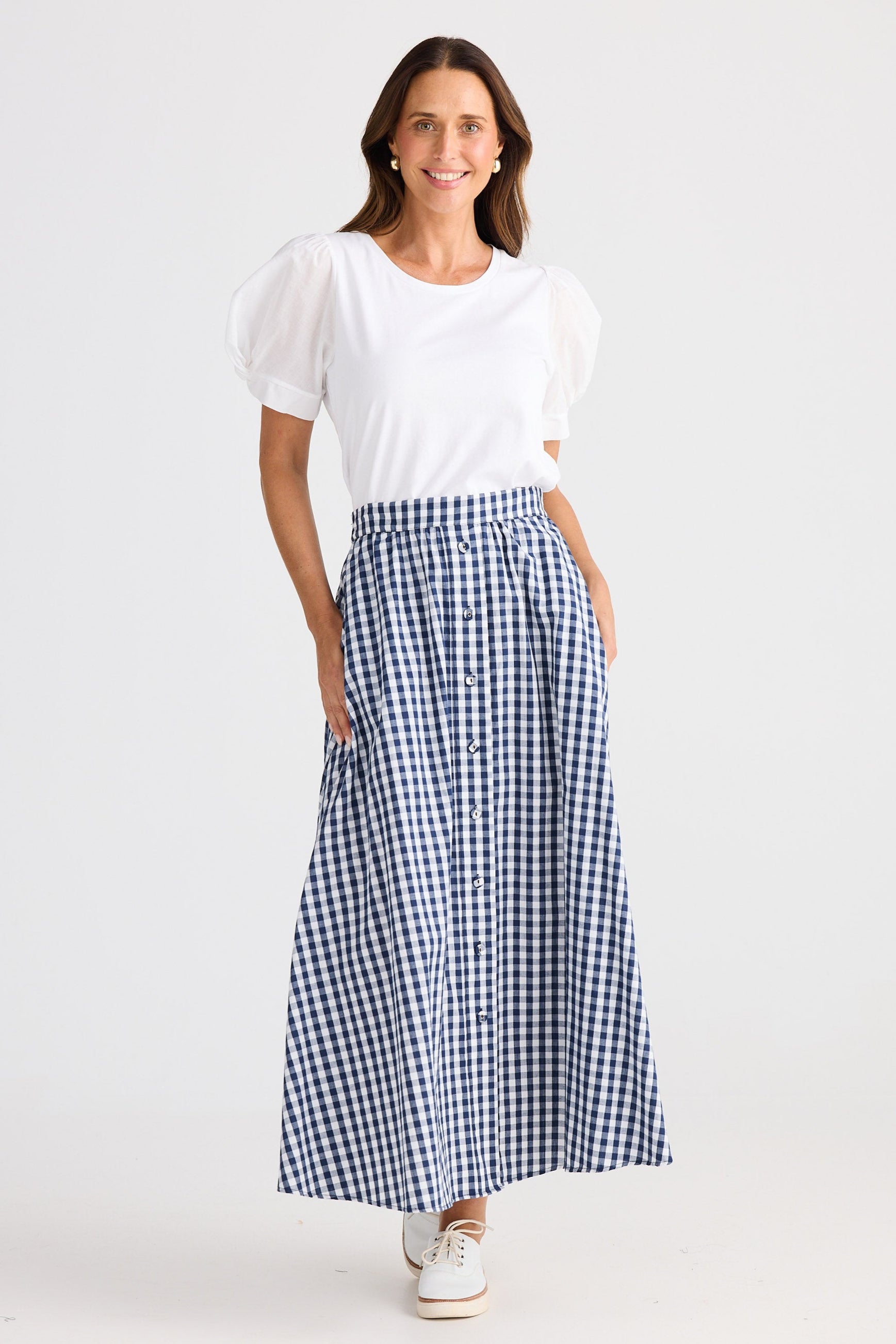 Woman wearing a white top and blue checkered skirt on a white background