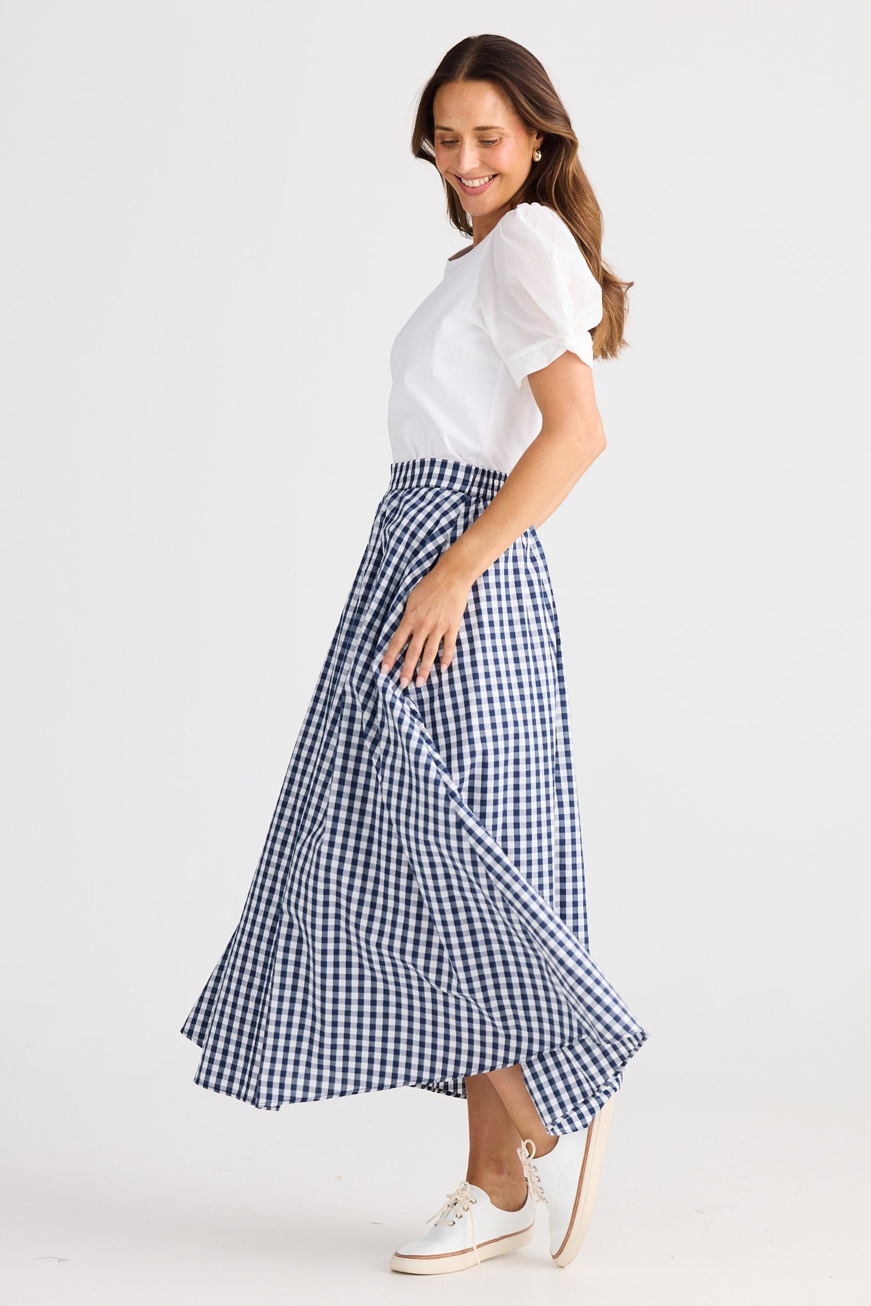 Woman wearing a white t-shirt and blue checkered skirt on a white background