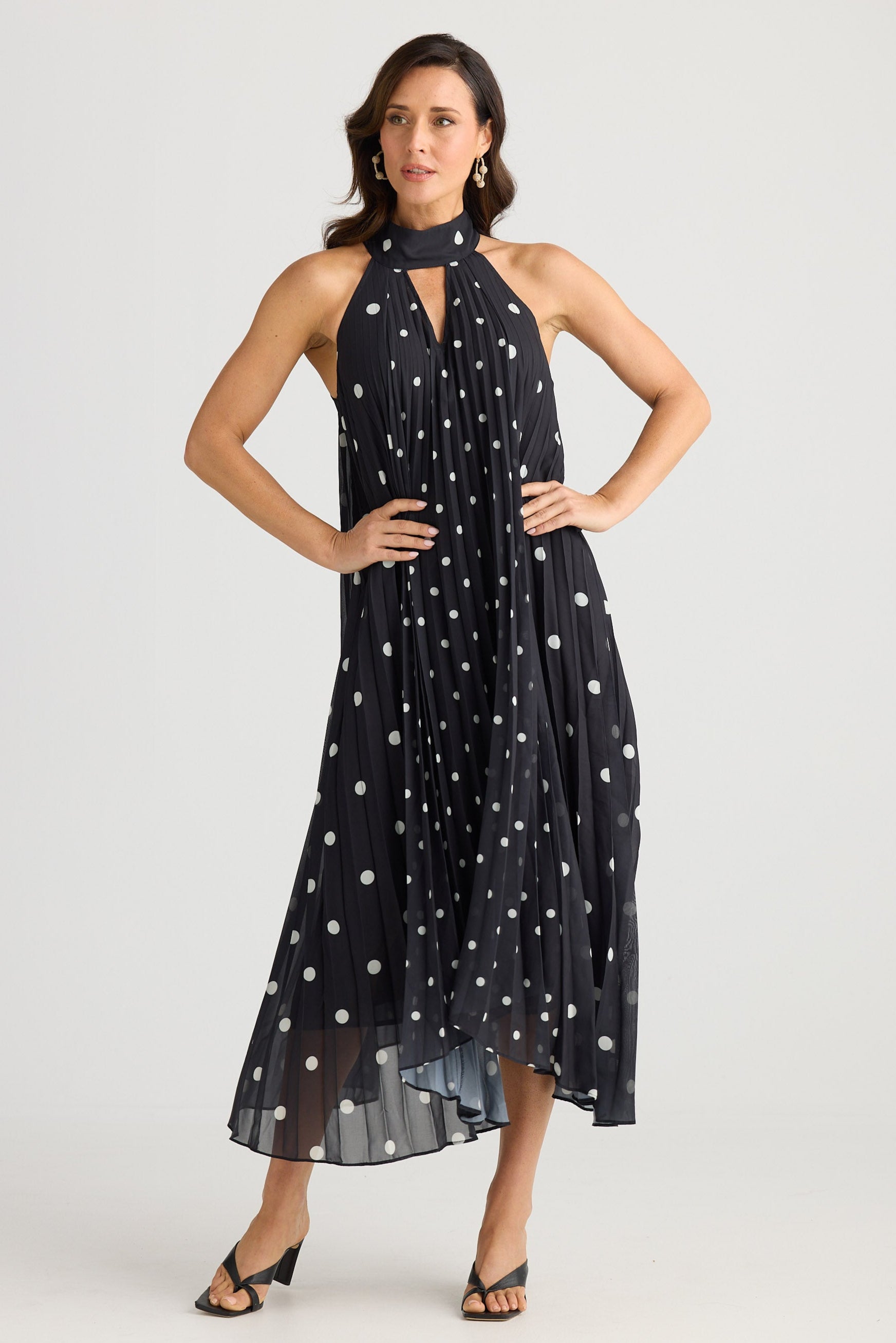 Woman wearing a black dress with white polka dots on a white background