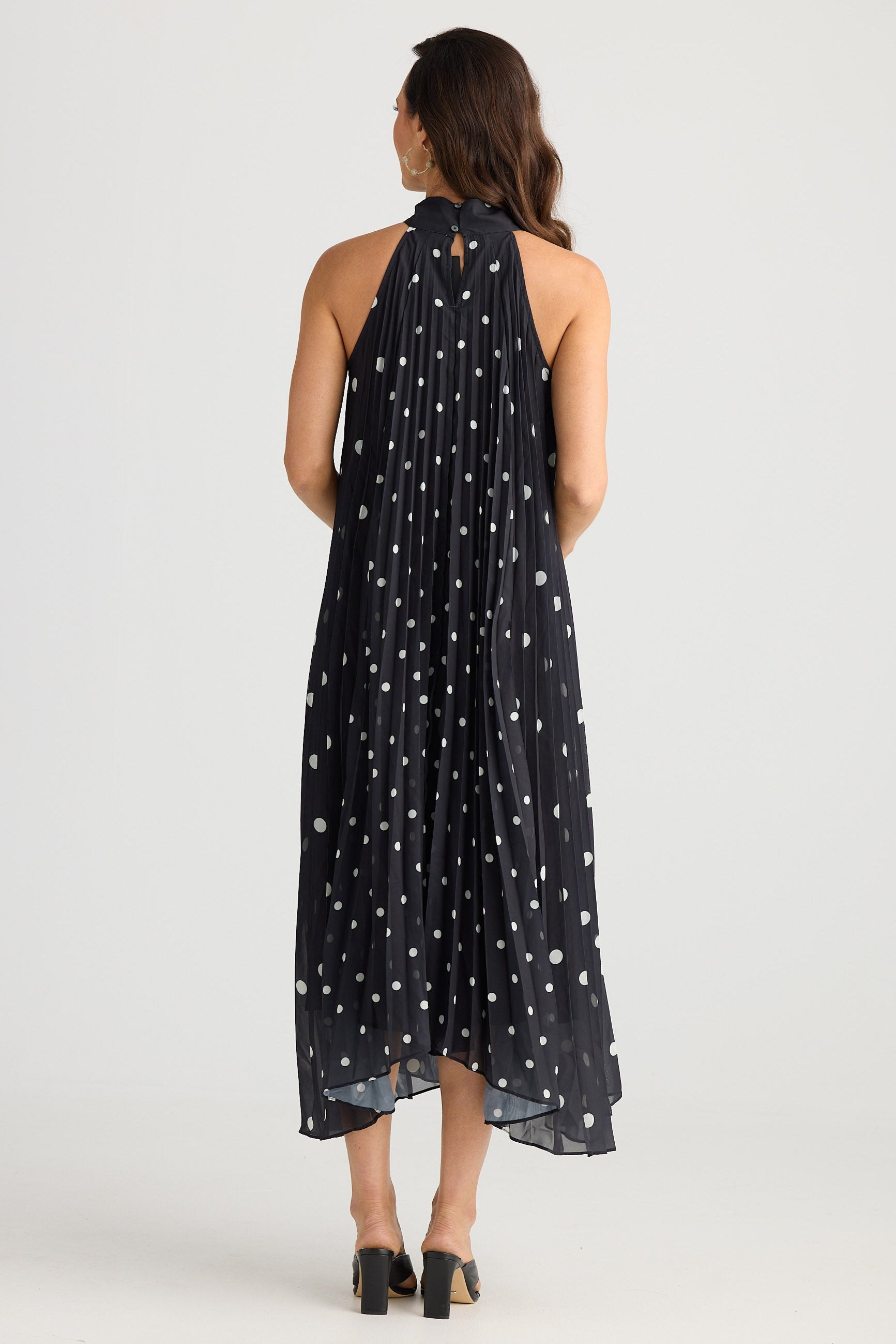 Woman wearing a black halter neck dress with white star pattern on a white background