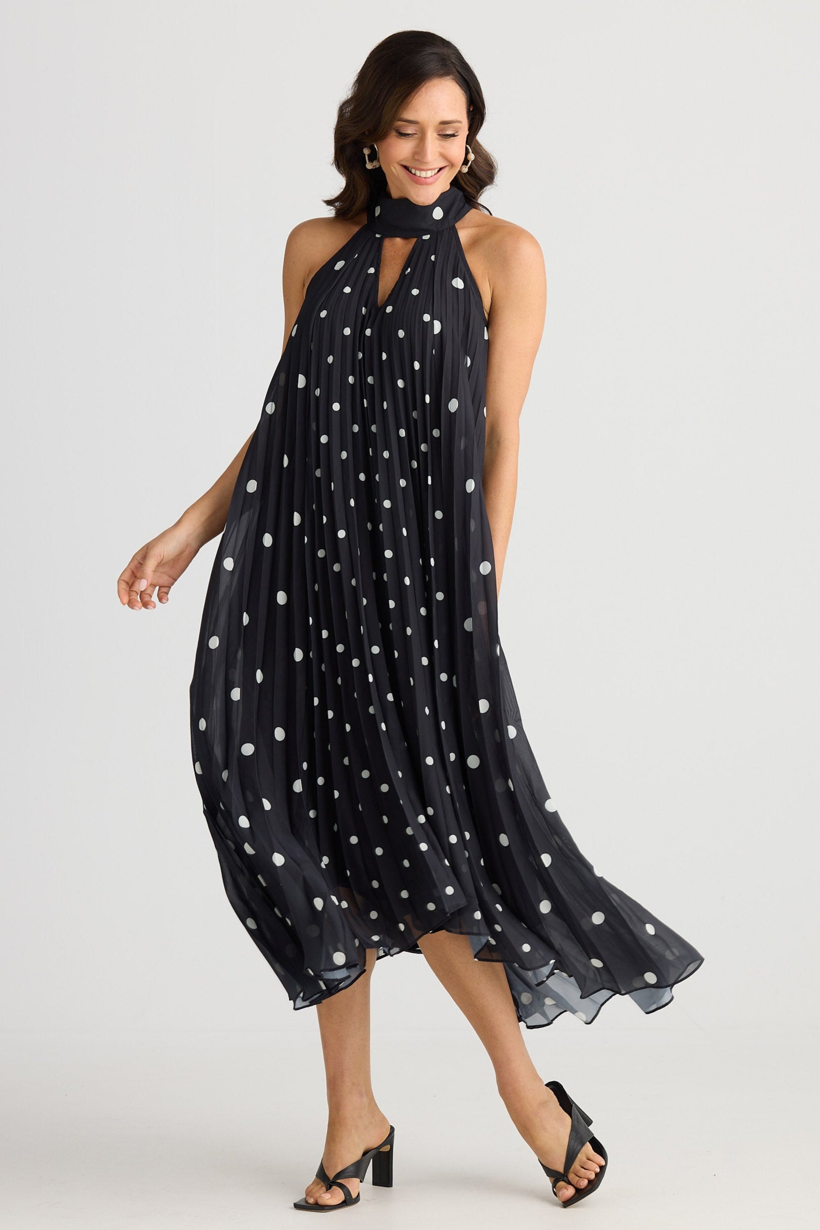 Woman wearing a black dress with white polka dots on a white background
