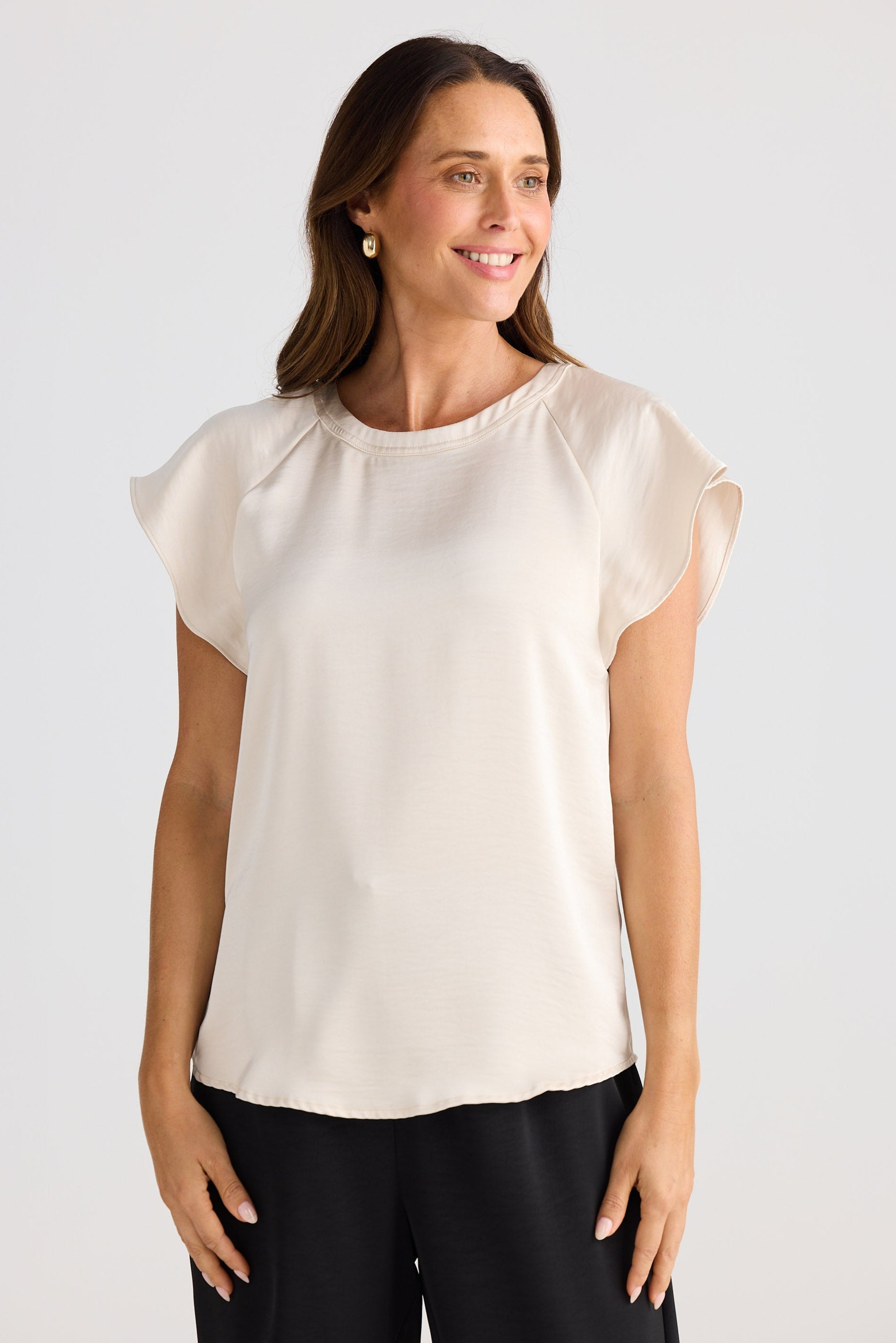 Woman wearing a white blouse with ruffled sleeves against a plain background
