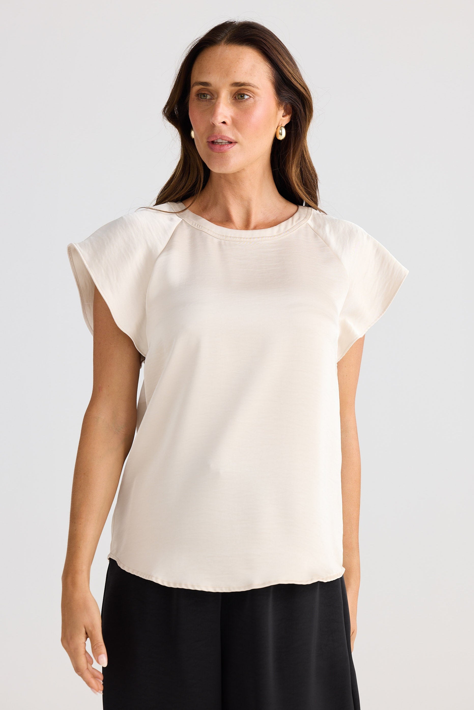Woman wearing a white blouse with ruffled sleeves against a plain background