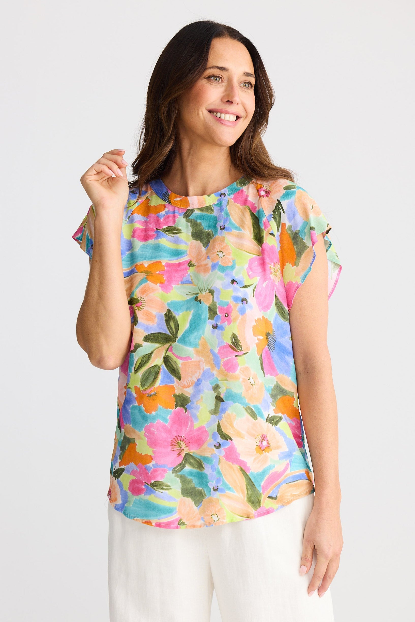 Woman wearing a colorful floral top against a white background