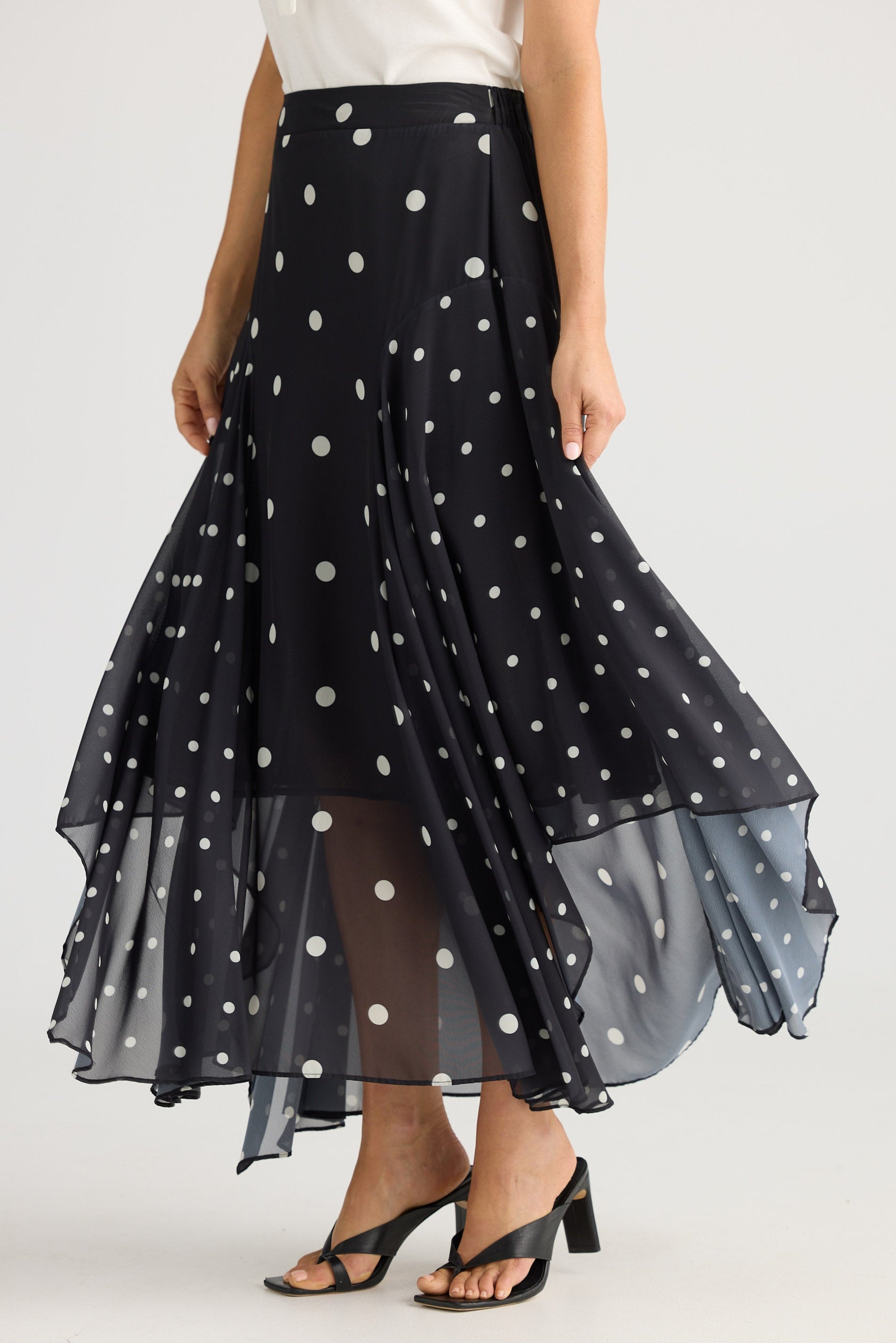 Black polka dot skirt with sheer overlay worn by a person on a white background