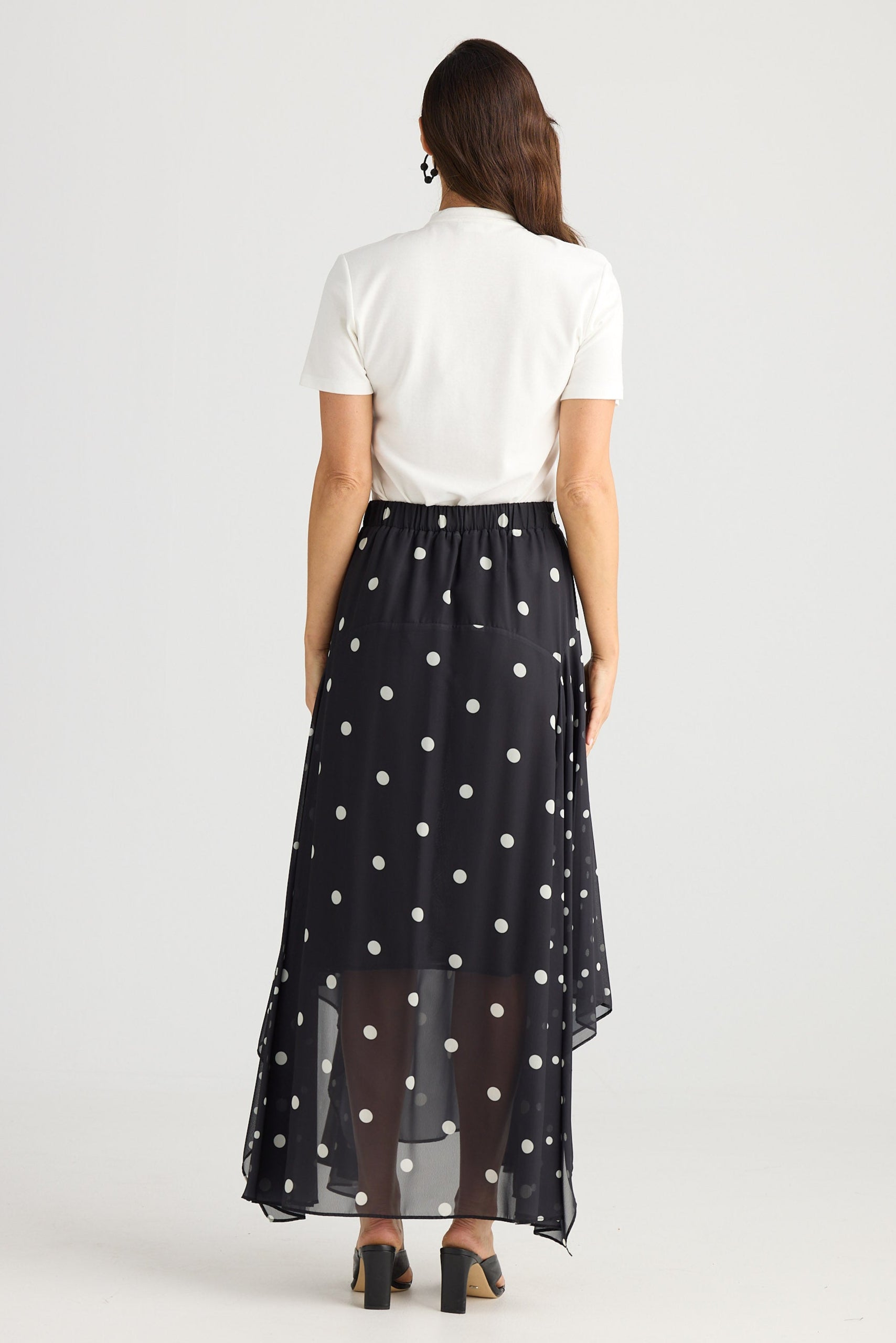 Woman wearing a white top and black polka dot skirt on a white background