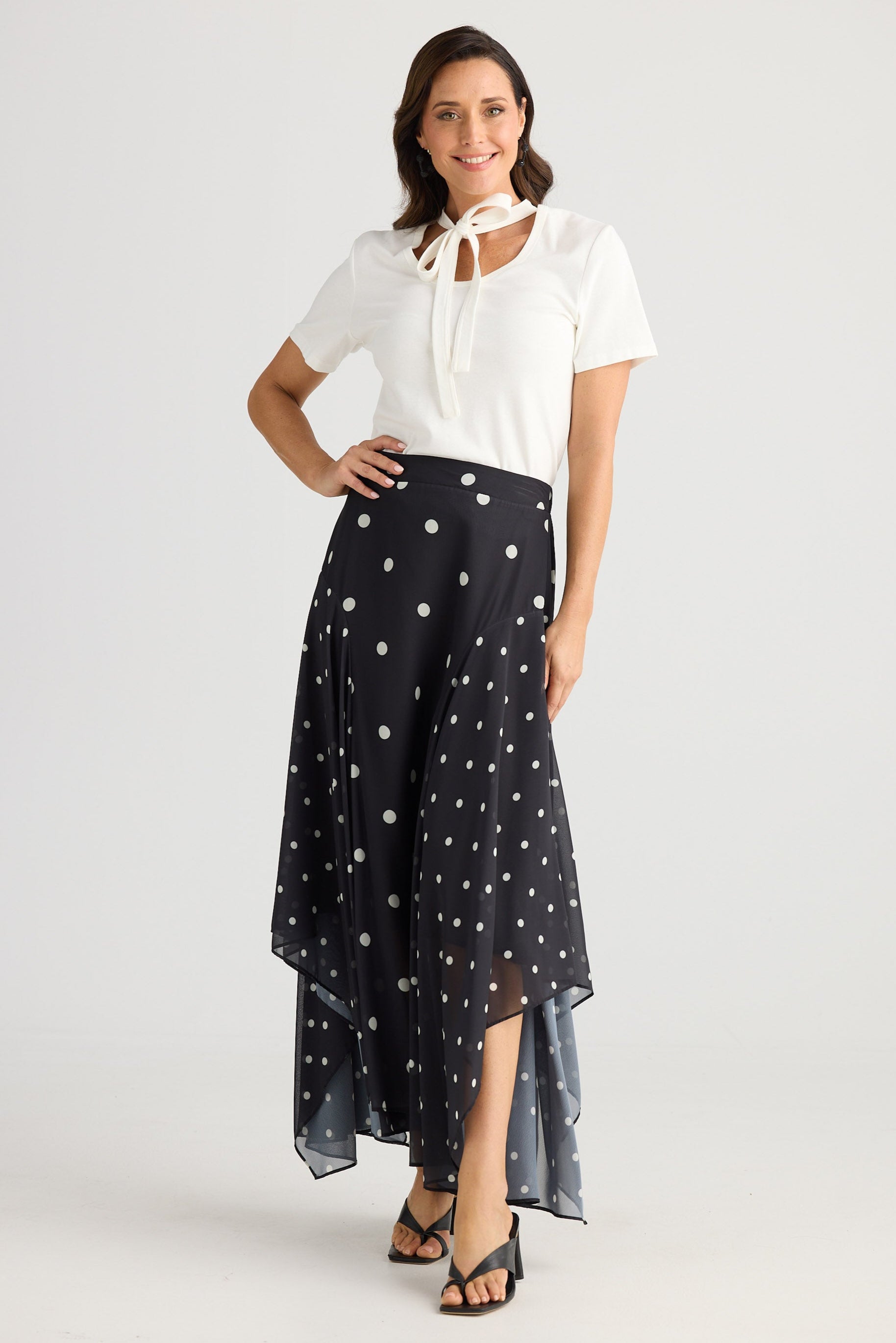 Woman wearing a white blouse and black polka dot skirt on a white background