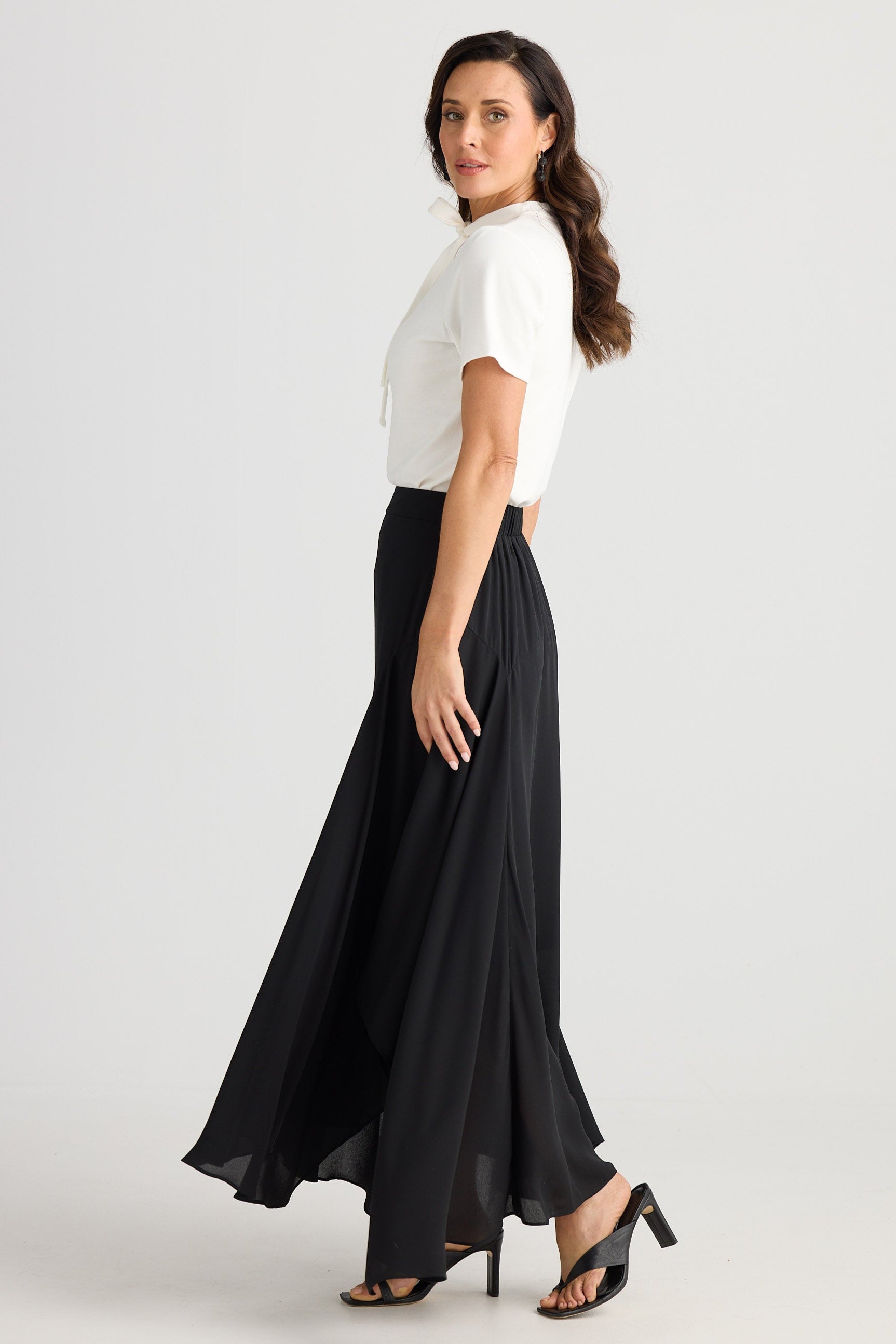 Woman wearing a white top and black skirt on a white background