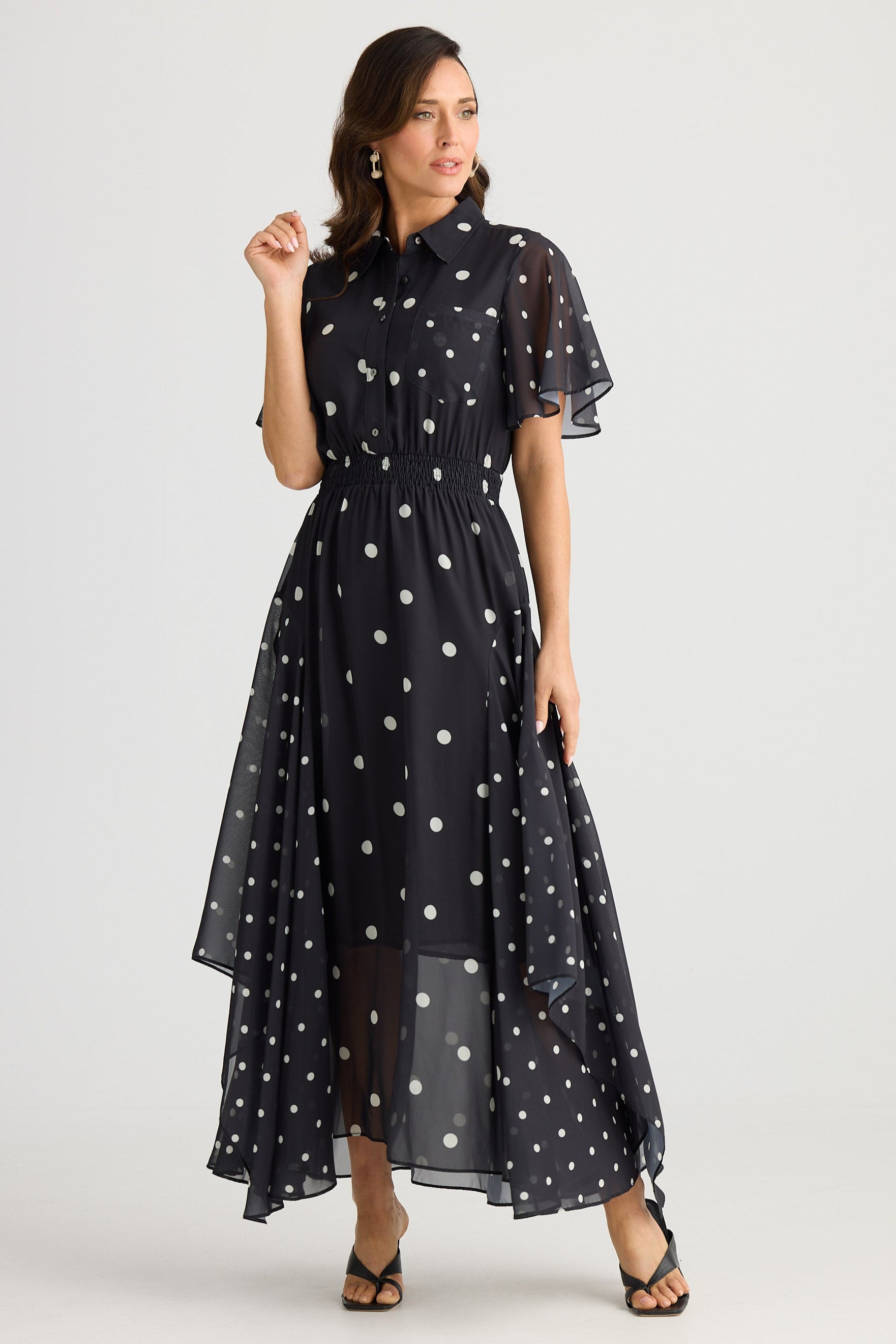 Woman wearing a black dress with white polka dots on a white background