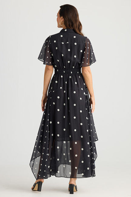 Woman wearing a black dress with white polka dots from behind on a white background