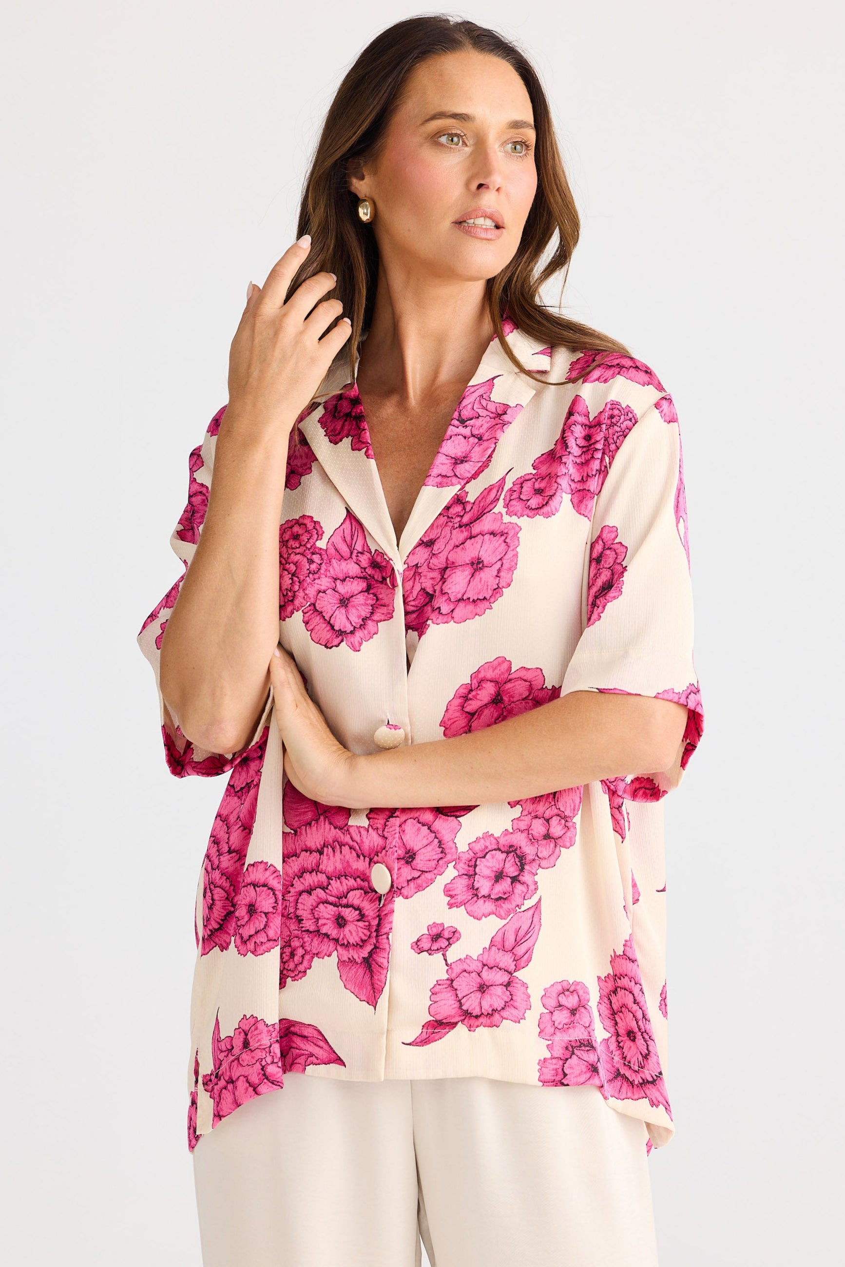 Woman wearing a pink floral blouse against a white background