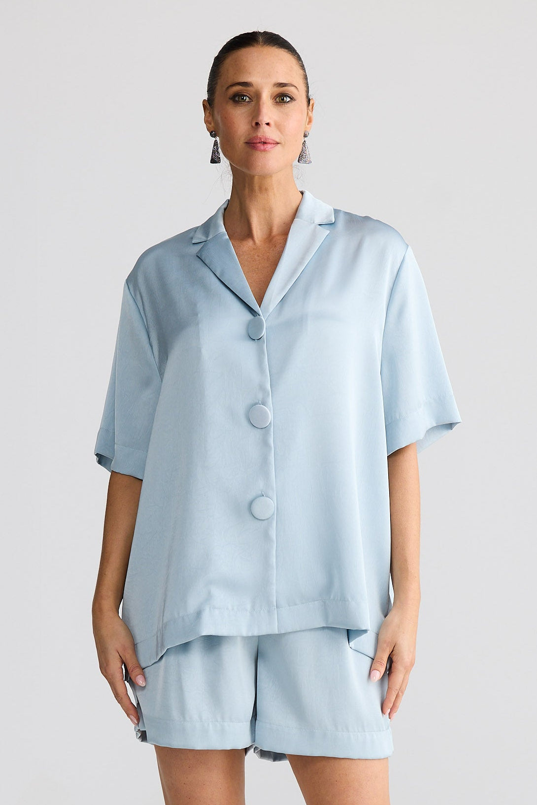 Woman wearing a light blue silky set on a white background