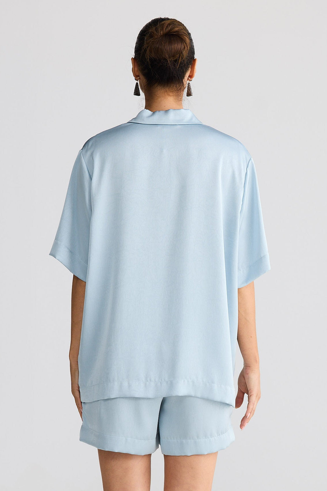 Person wearing a light blue outfit on a white background