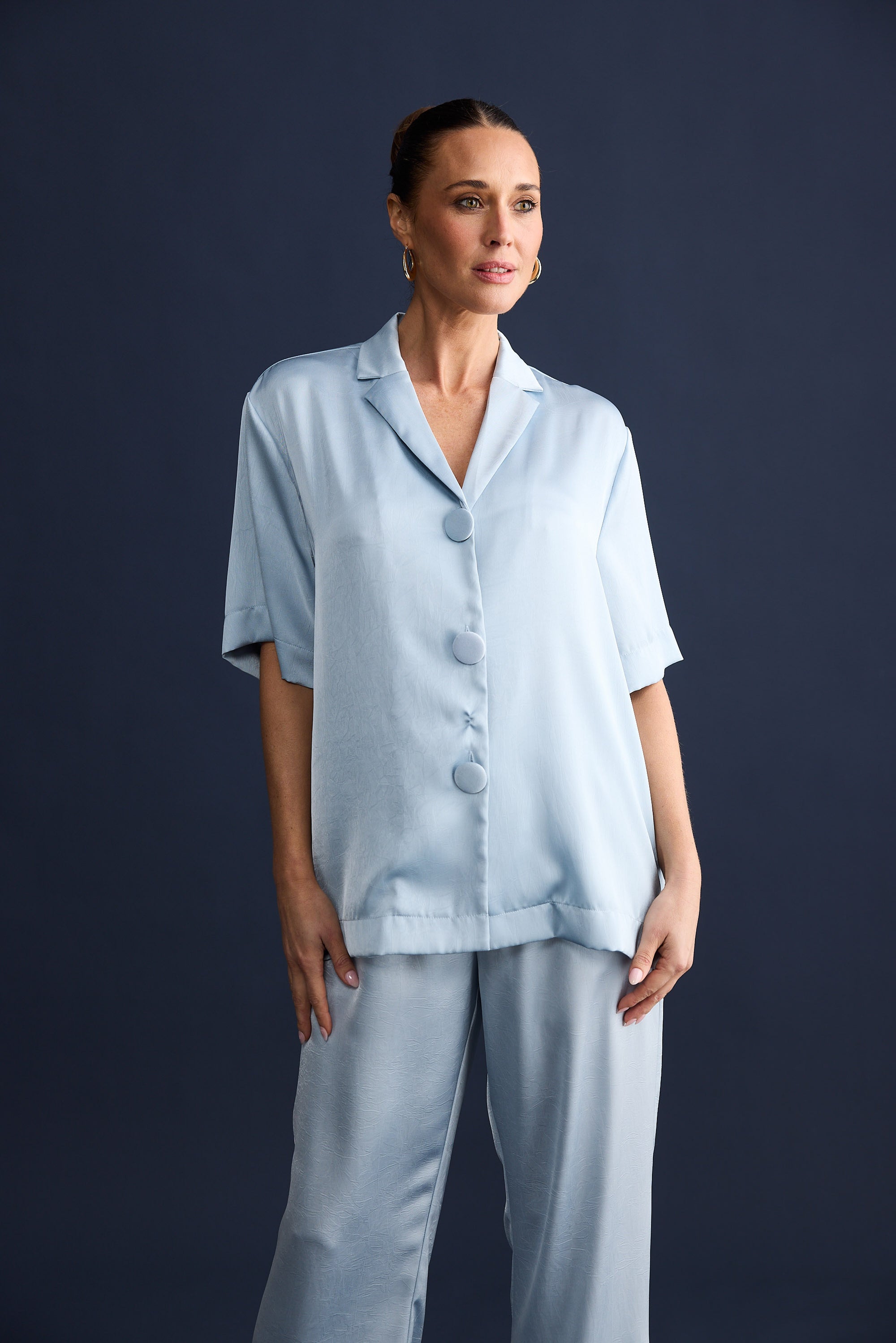 Woman wearing a light blue pajama set against a dark background