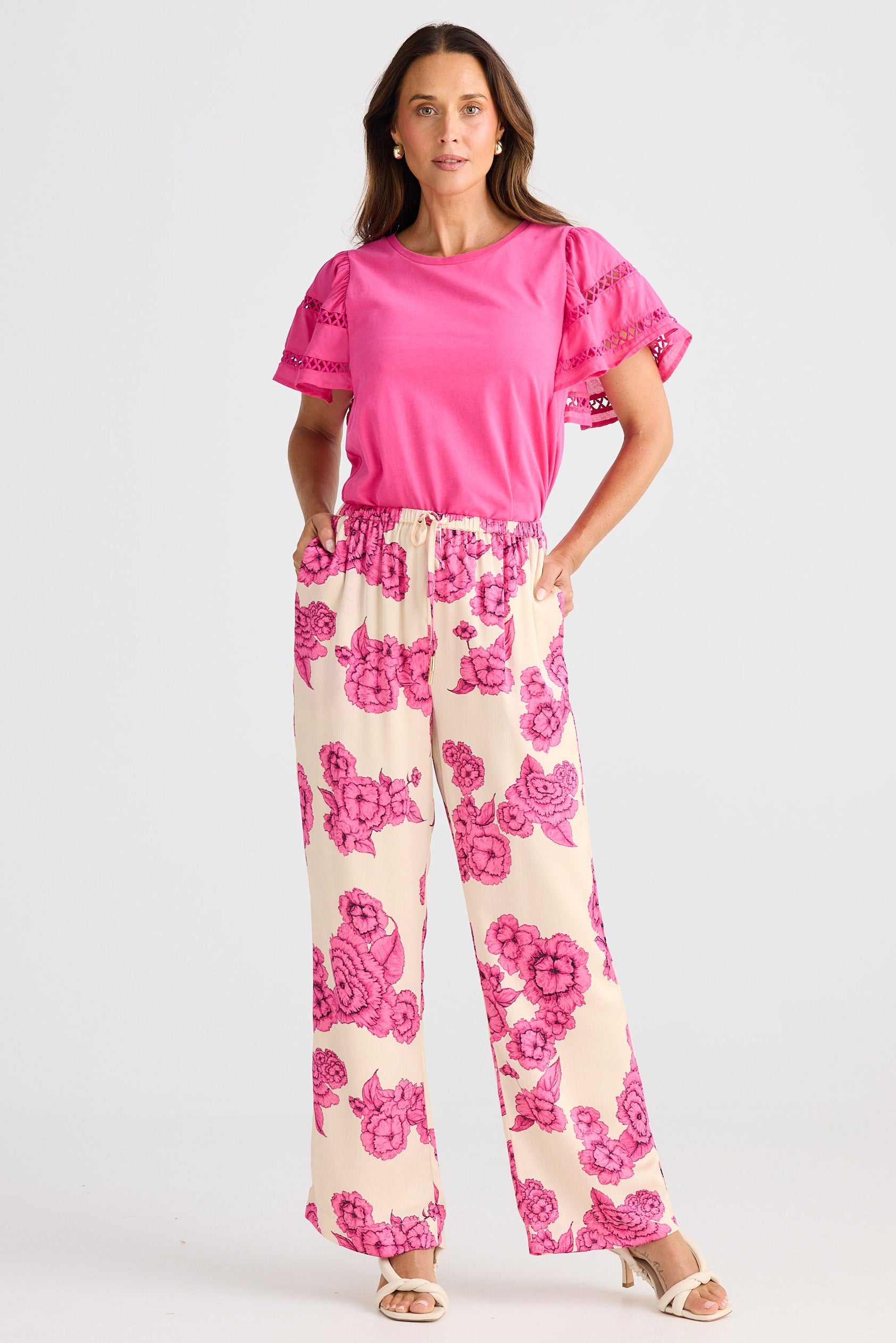 Woman wearing a pink top and floral pants on a white background