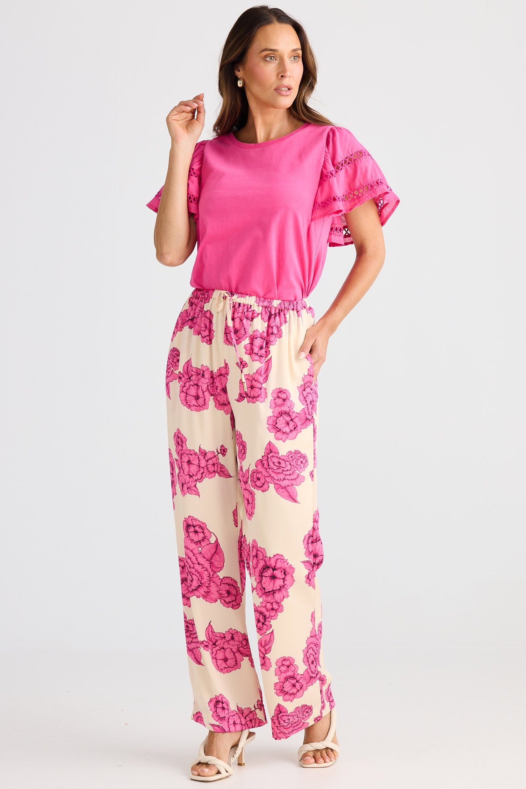 Woman wearing a pink top and floral pants on a white background