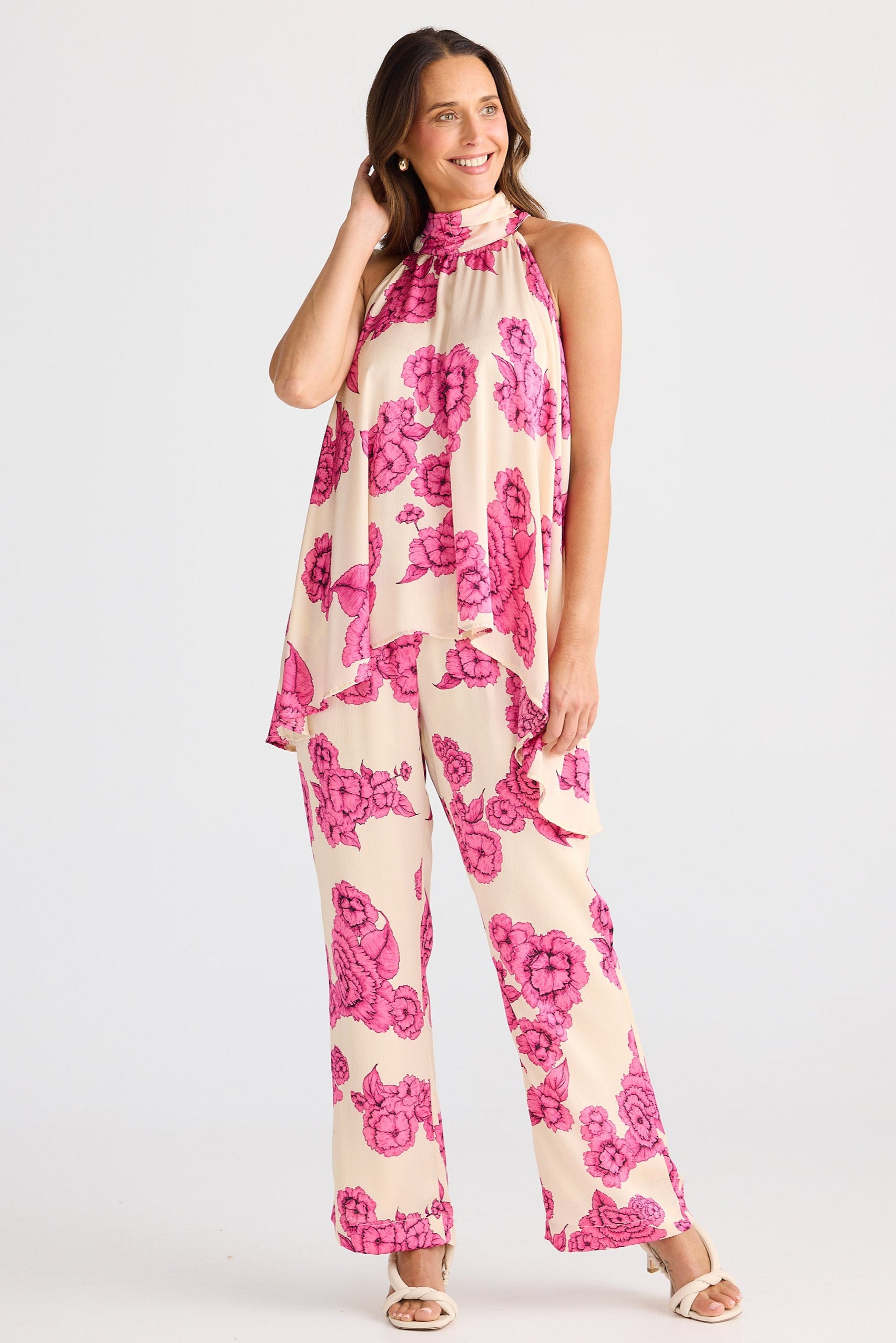 Woman wearing a pink floral top and pants on a white background