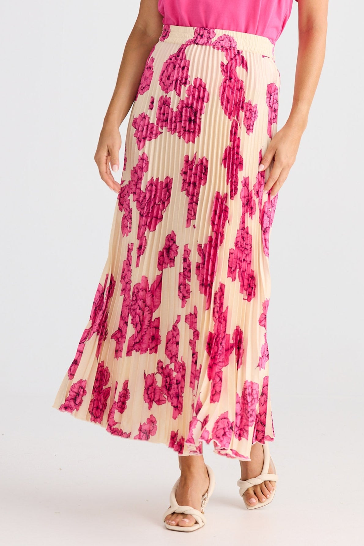 Woman wearing a pink top and patterned skirt on a white background