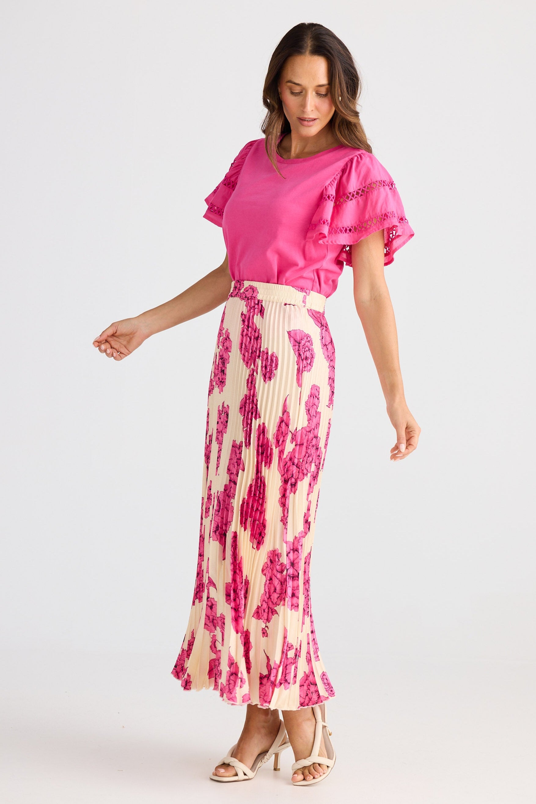 Woman wearing a pink top and floral skirt on a white background