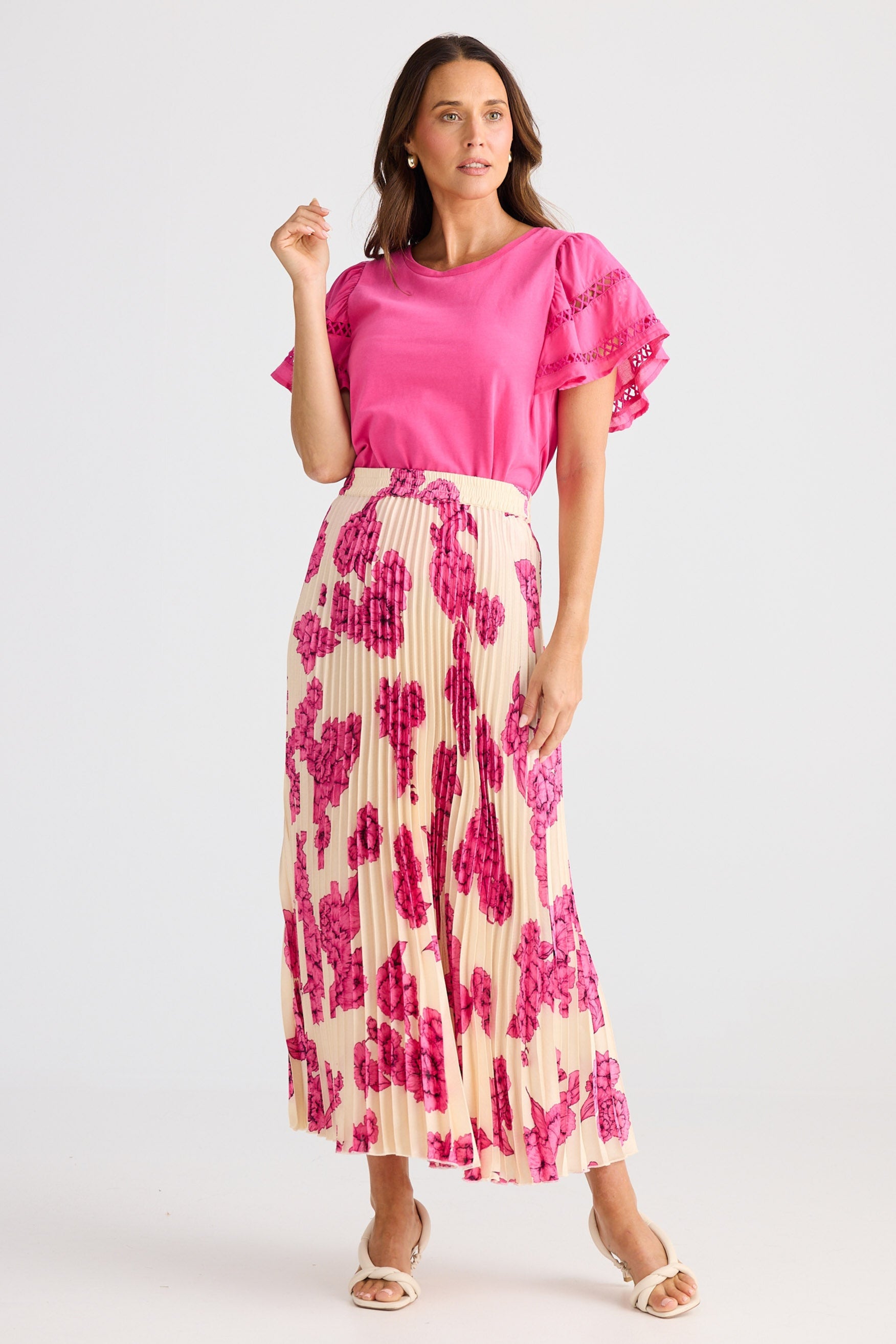 Woman wearing a pink top and floral skirt on a white background