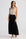 Woman wearing a beige sleeveless top and black pleated skirt on a white background