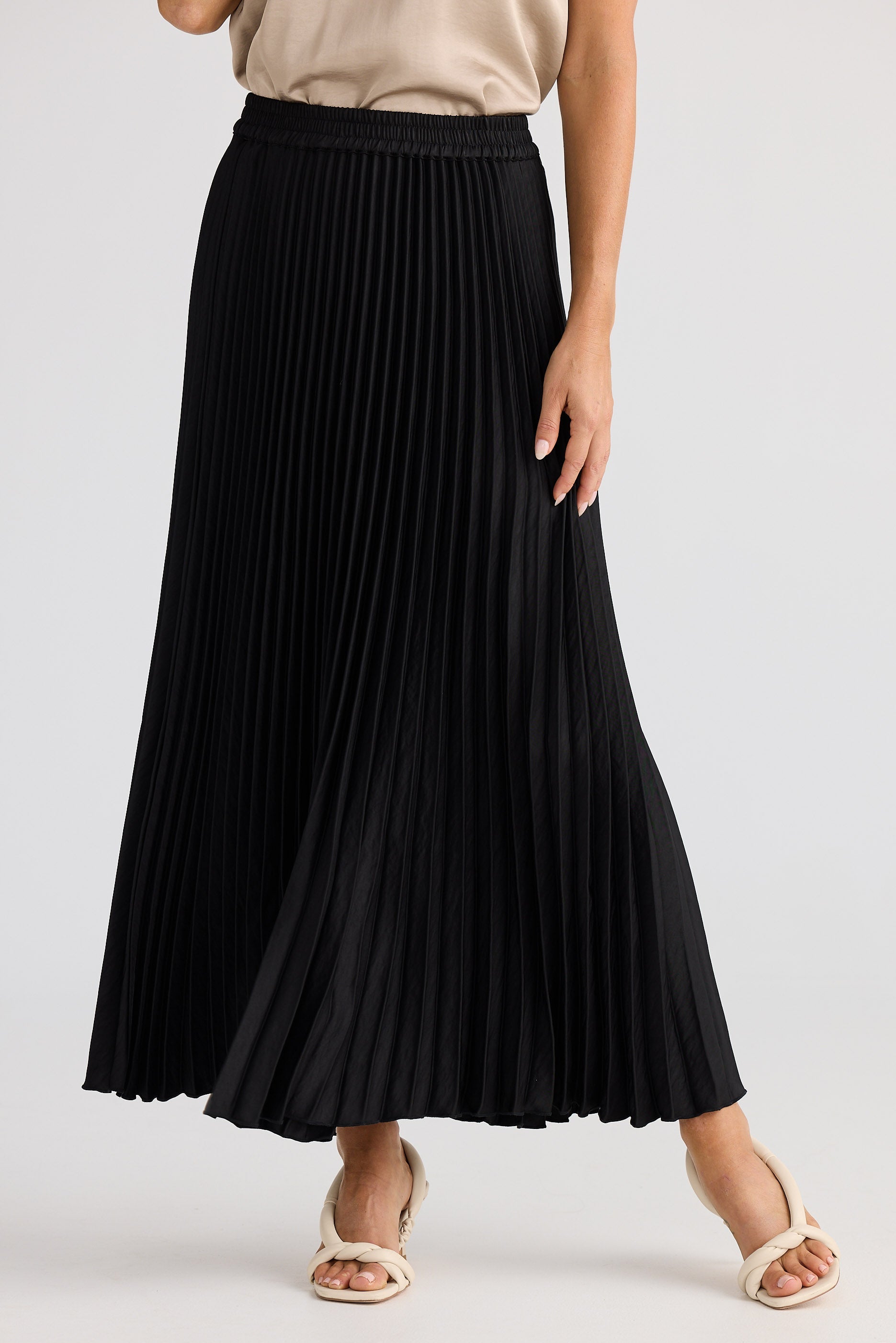 Black pleated skirt worn by a person on a white background