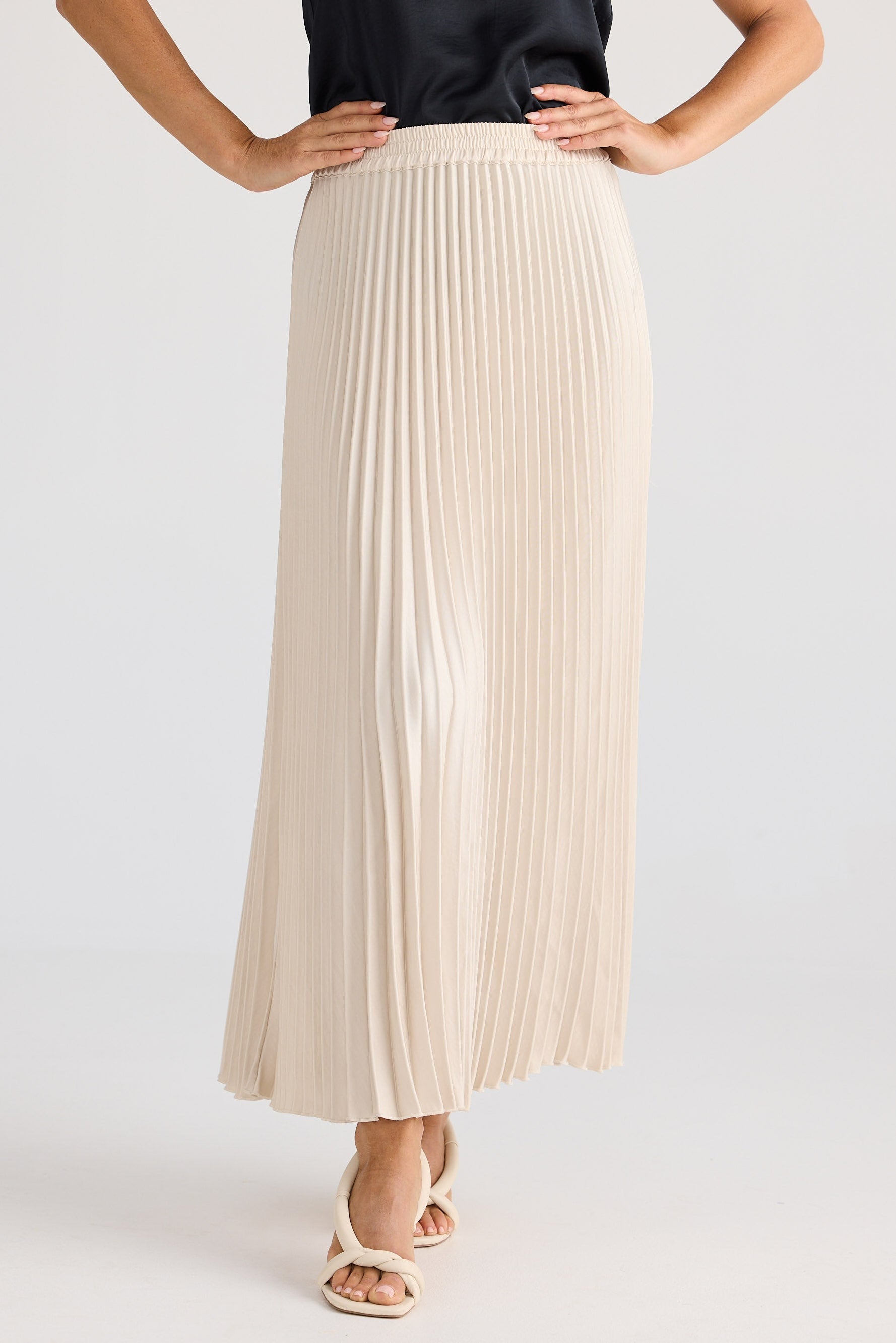 Person wearing a beige pleated skirt on a white background