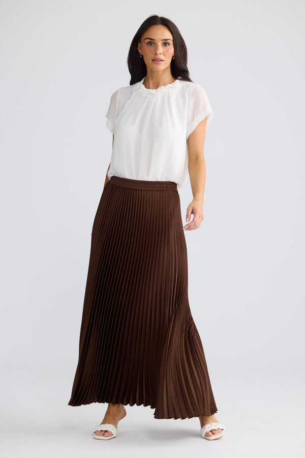 Model wearing Alias Pleated Skirt in chocolate brown by Brave + True, front view.