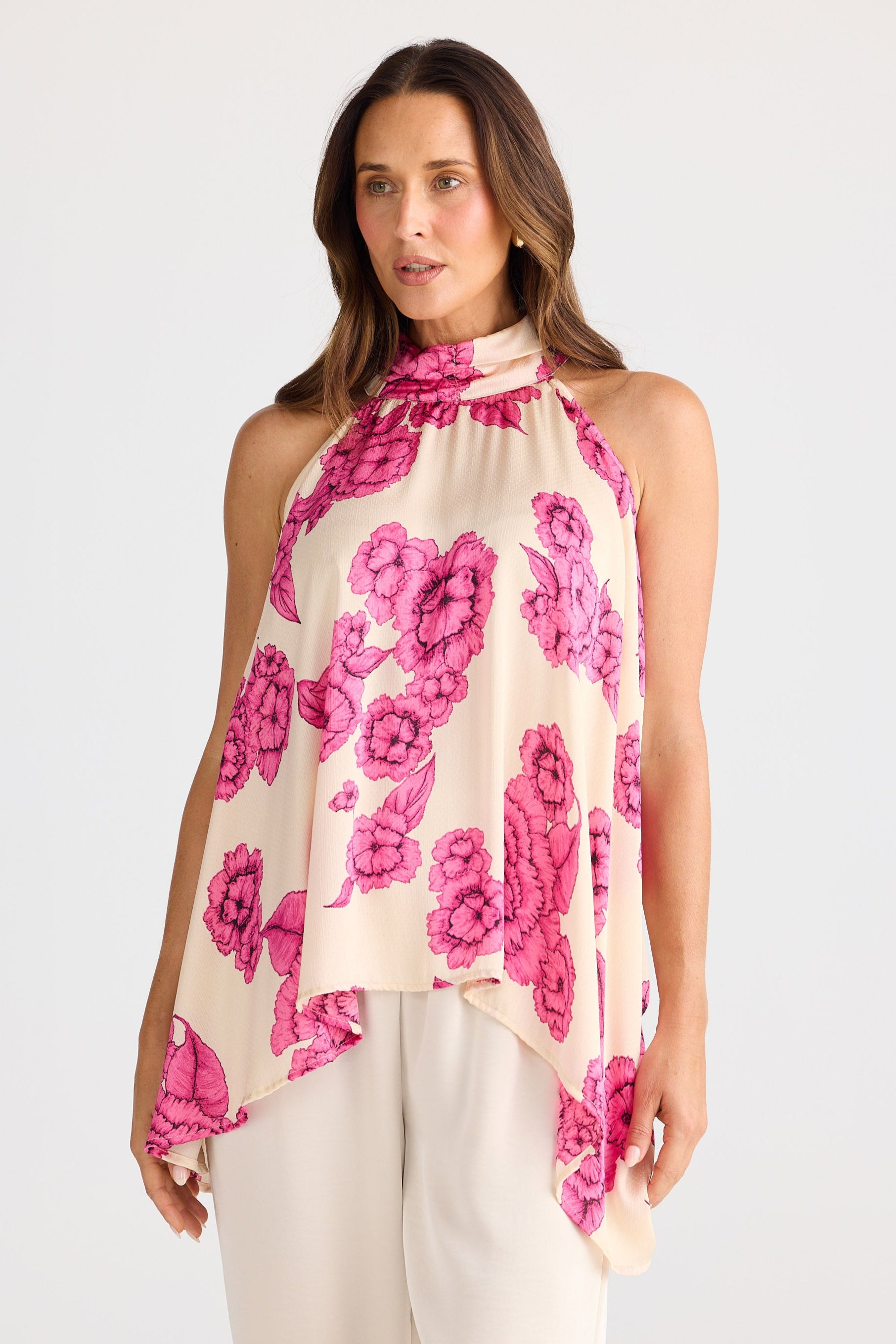 Woman wearing a sleeveless top with pink floral pattern on a white background
