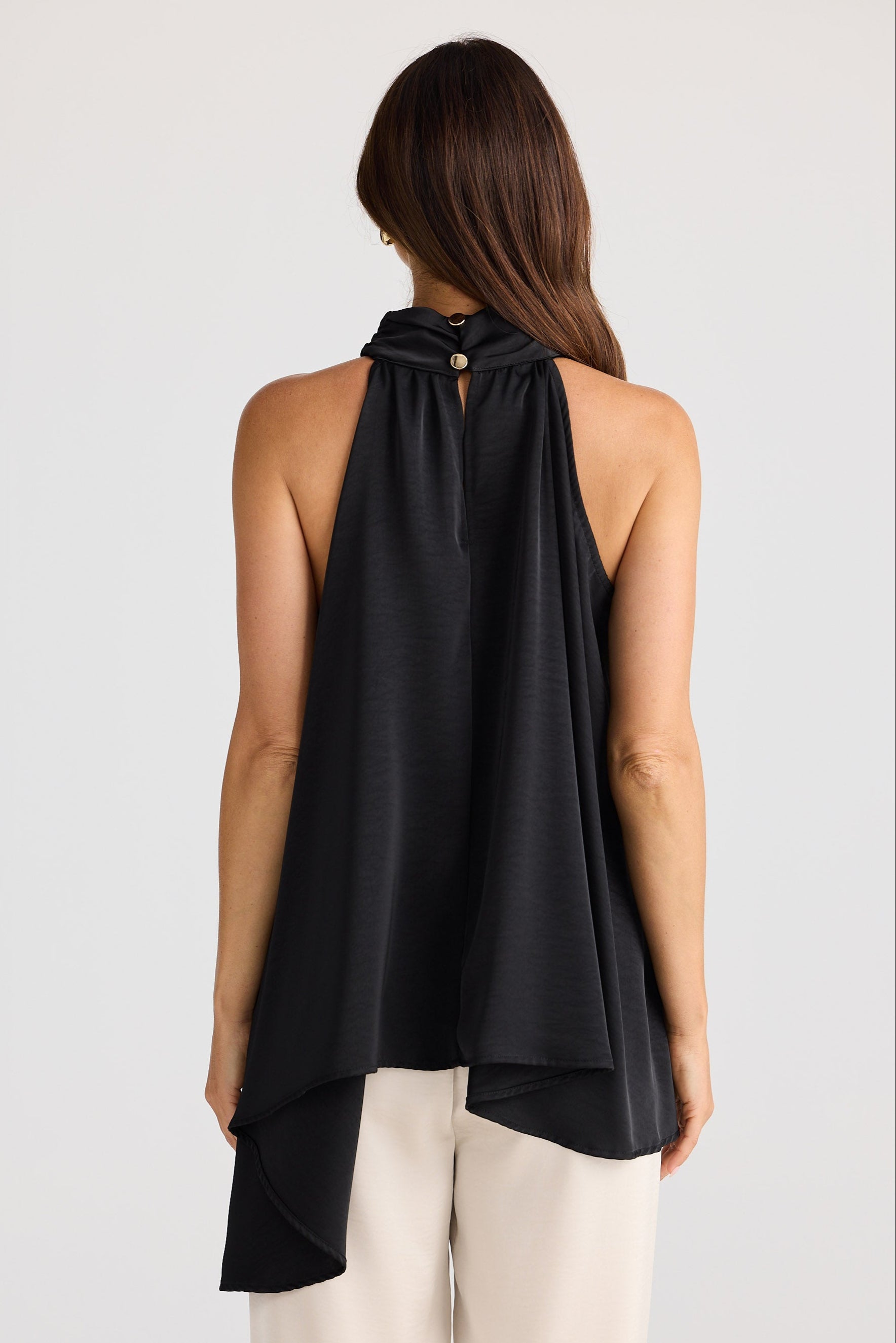 Woman wearing a black halter neck top with a plain background