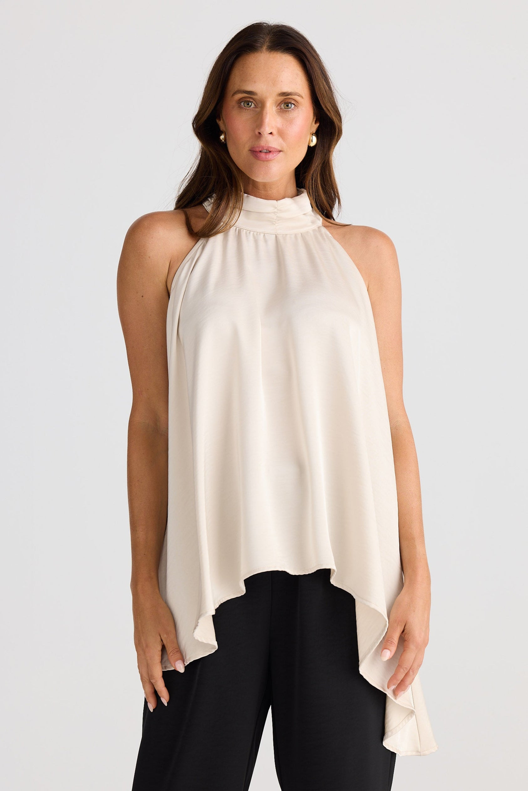 Woman wearing a white halter neck top and black pants on a white background