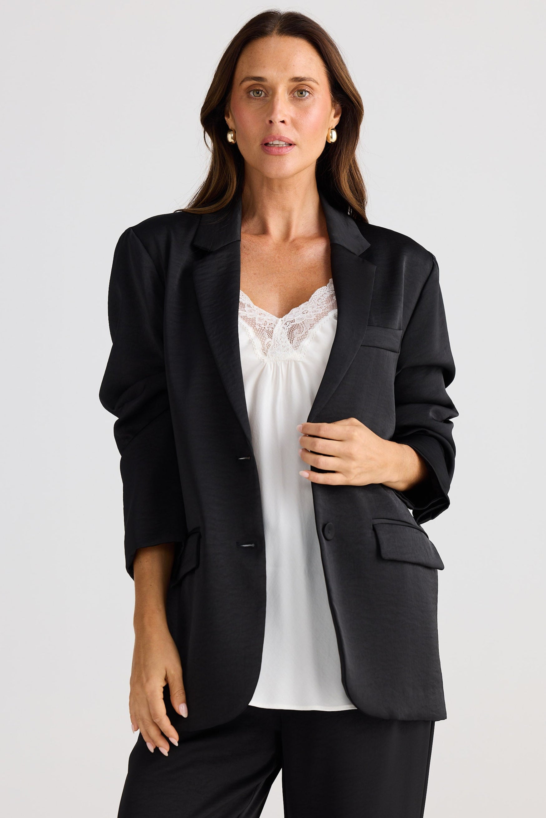 Woman wearing a black blazer over a white top on a plain background