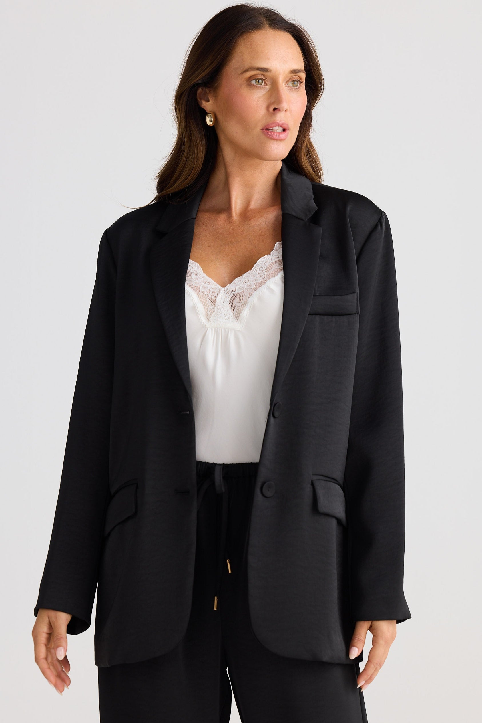 Woman wearing a black blazer over a white top on a plain background