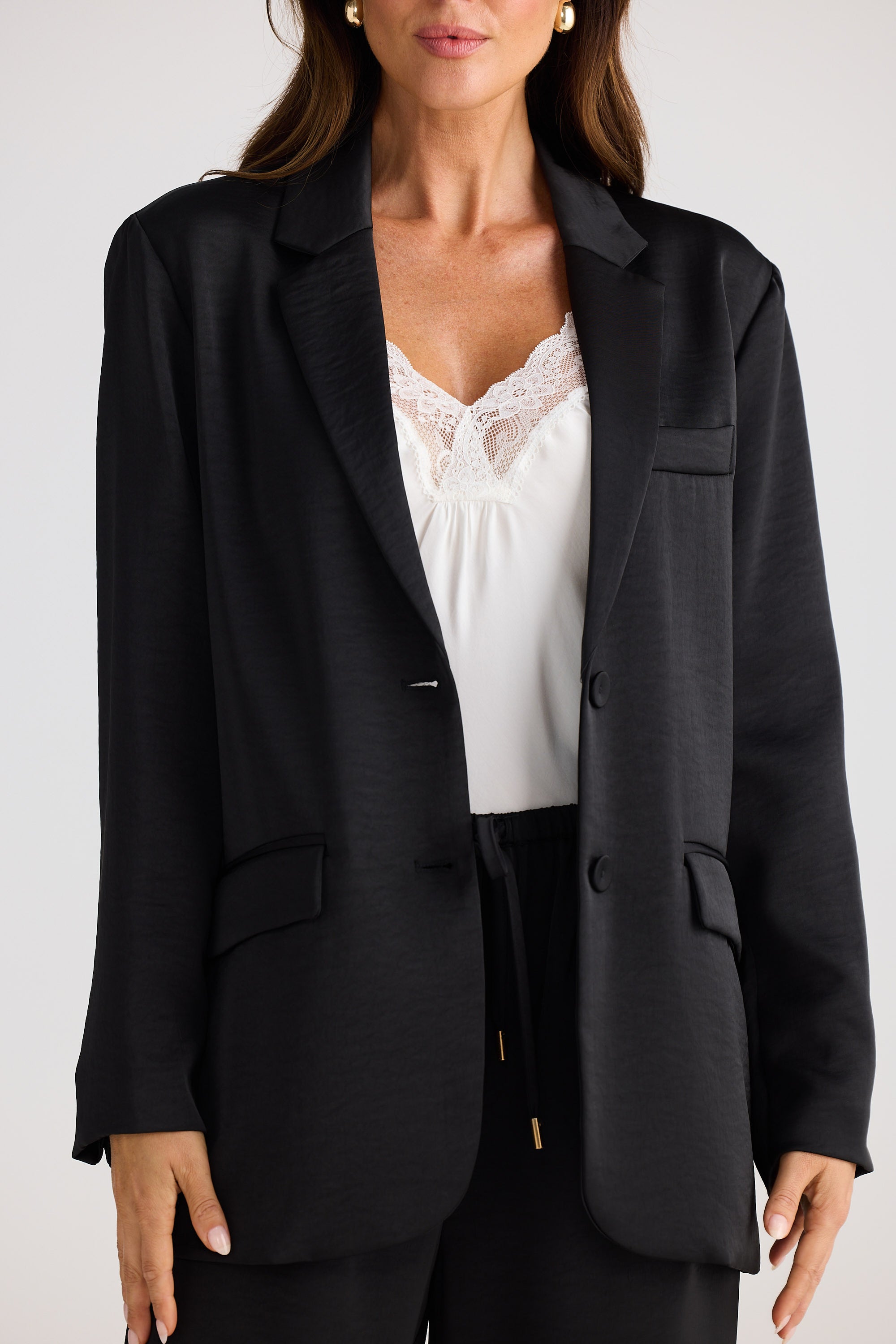 Person wearing a black blazer over a white top on a plain background