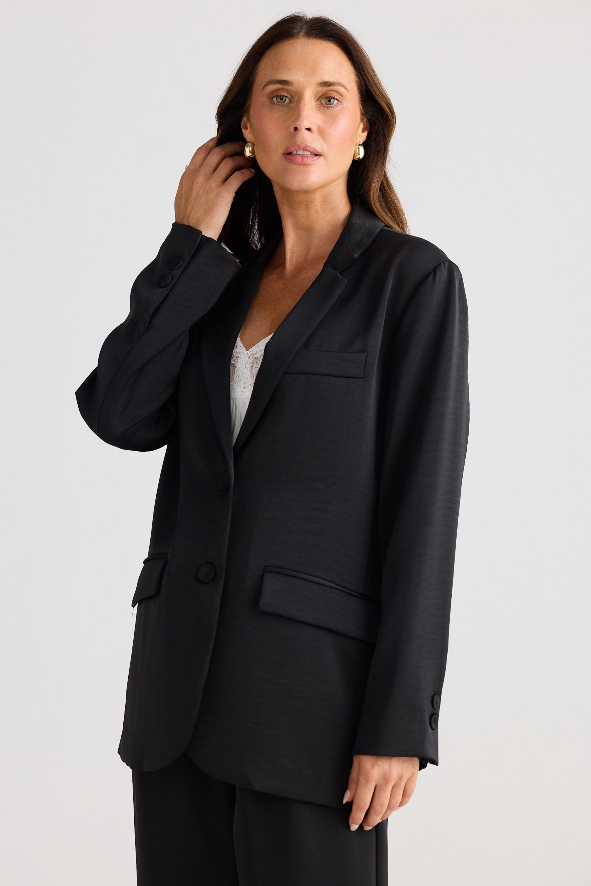 Woman wearing a black suit jacket on a white background