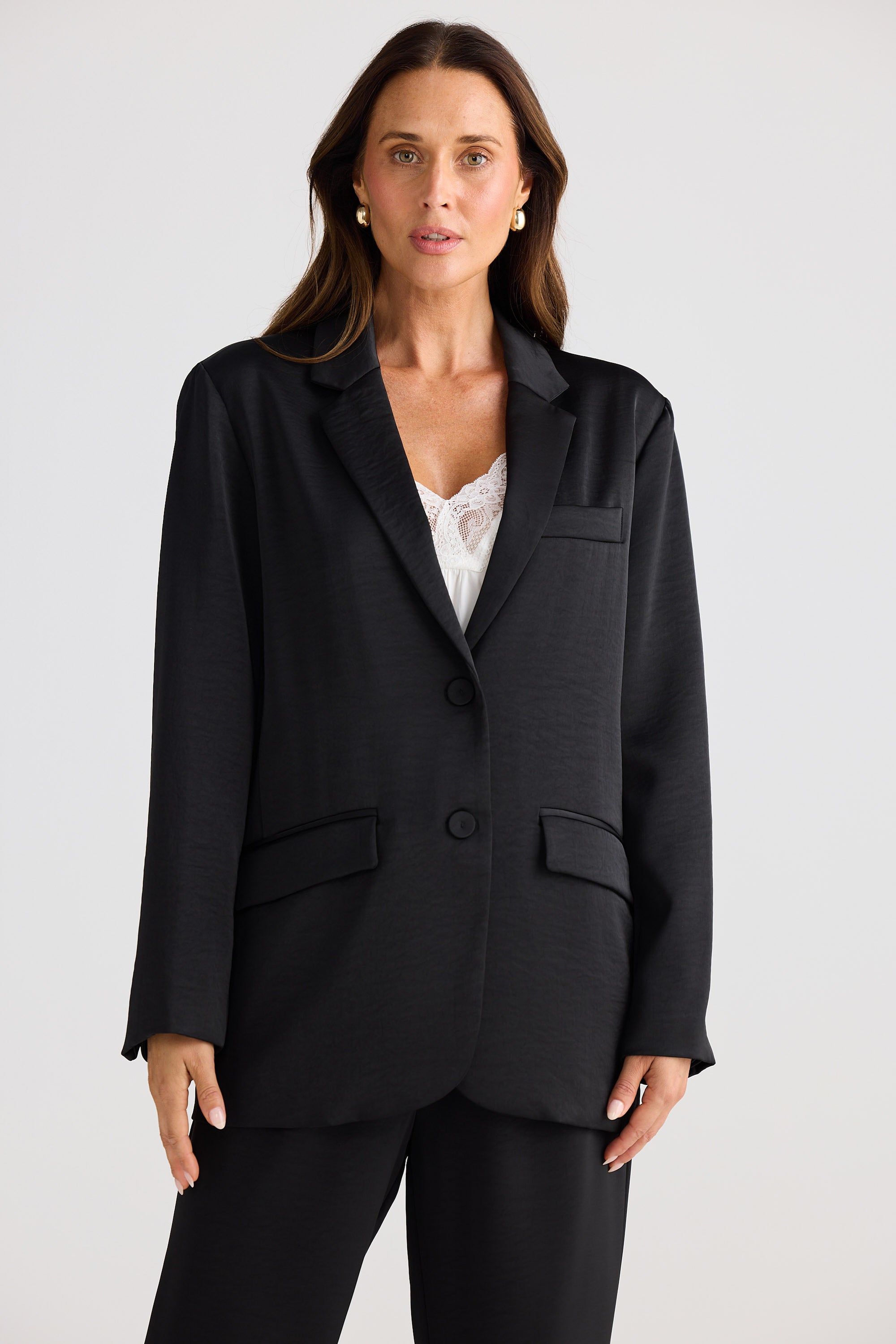Woman wearing a black suit jacket and pants on a white background