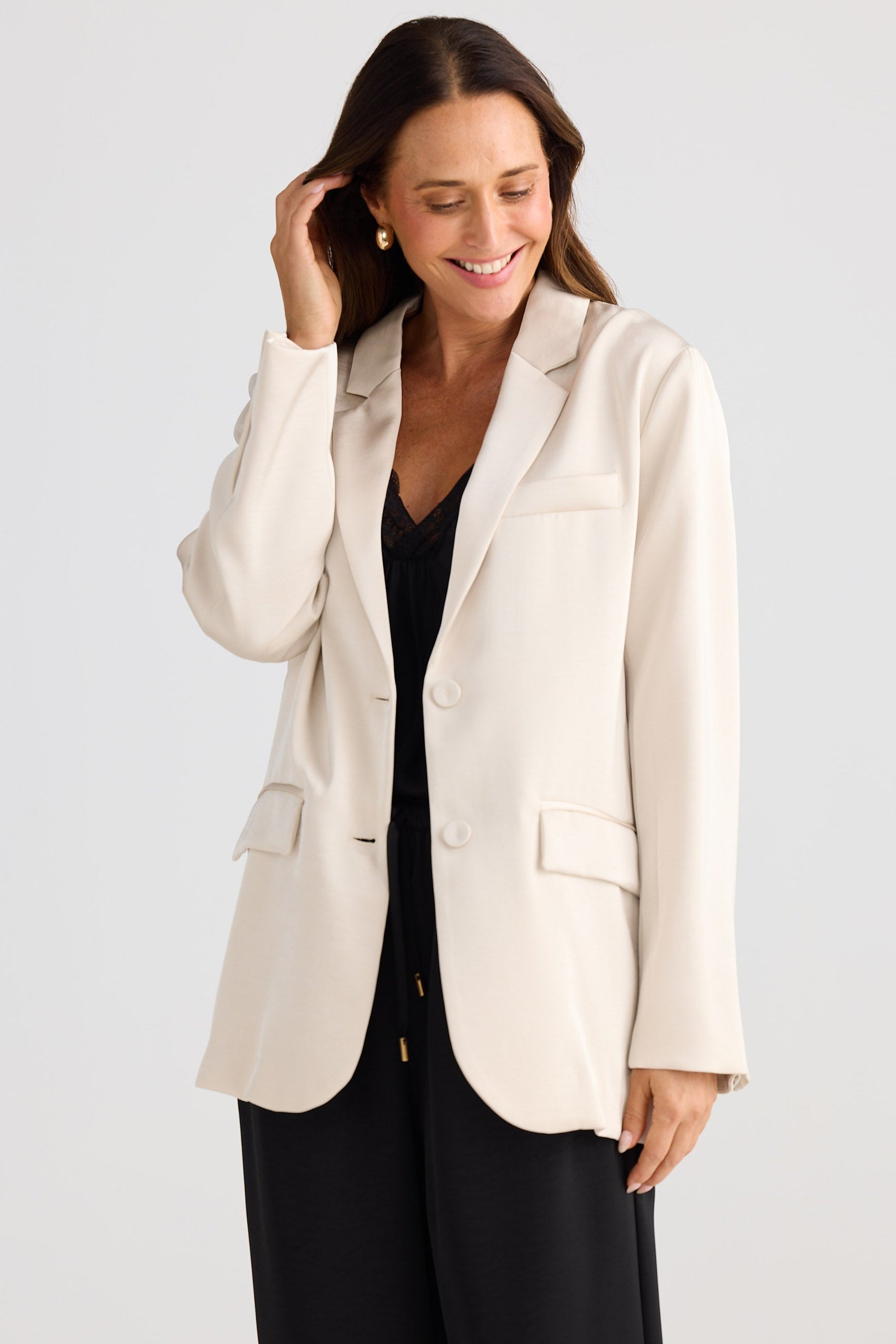 Woman wearing a beige blazer over a black top on a white background