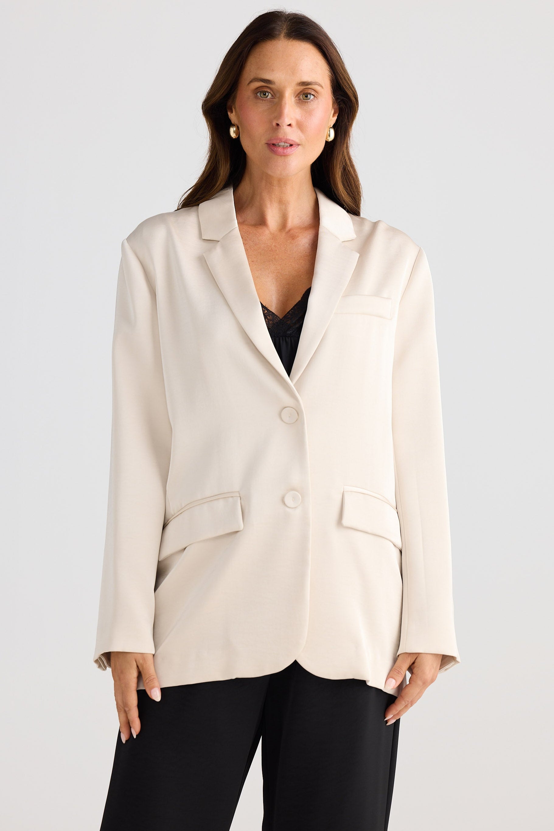 Woman wearing a cream blazer over a black top on a white background