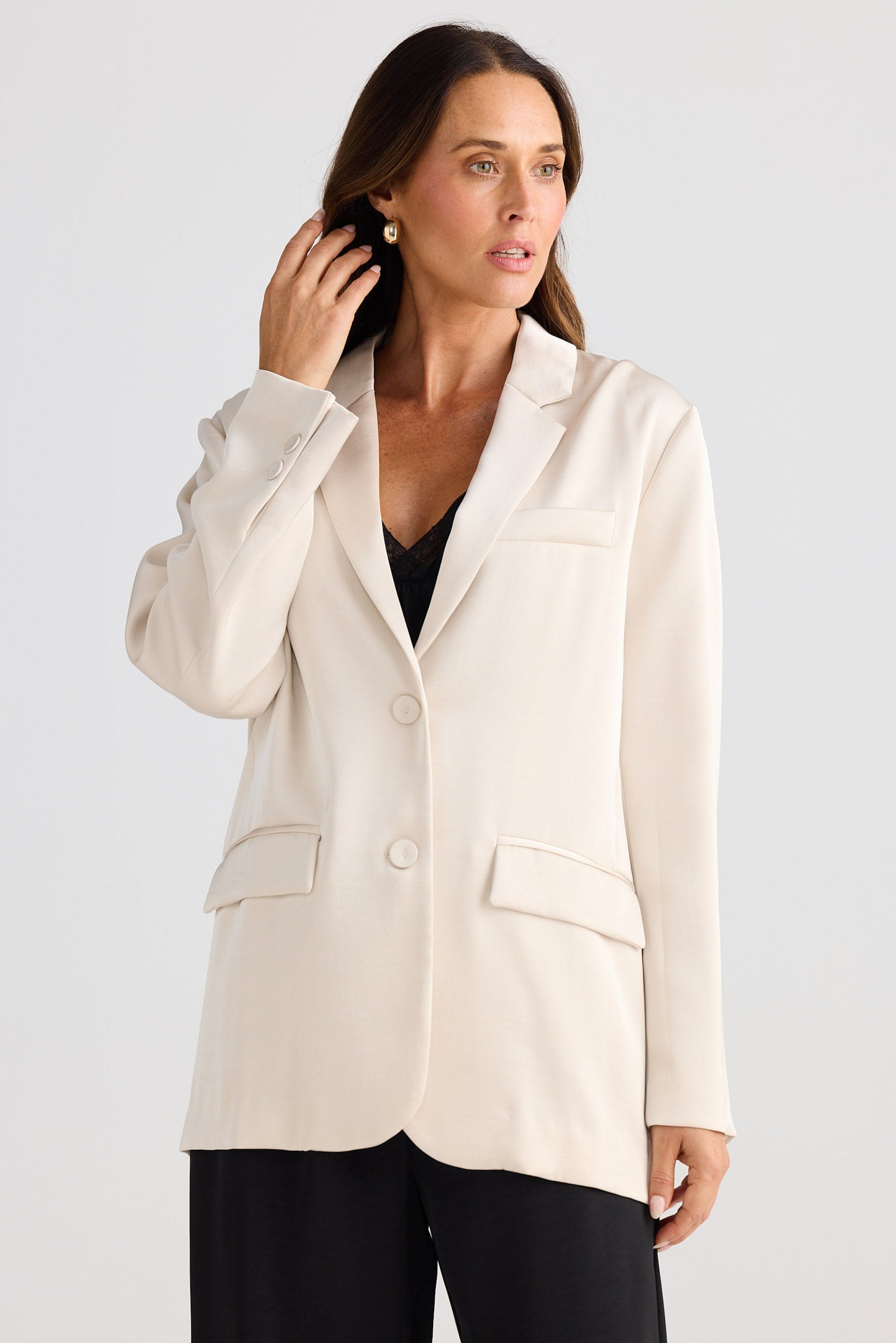 Woman wearing a cream blazer against a plain background